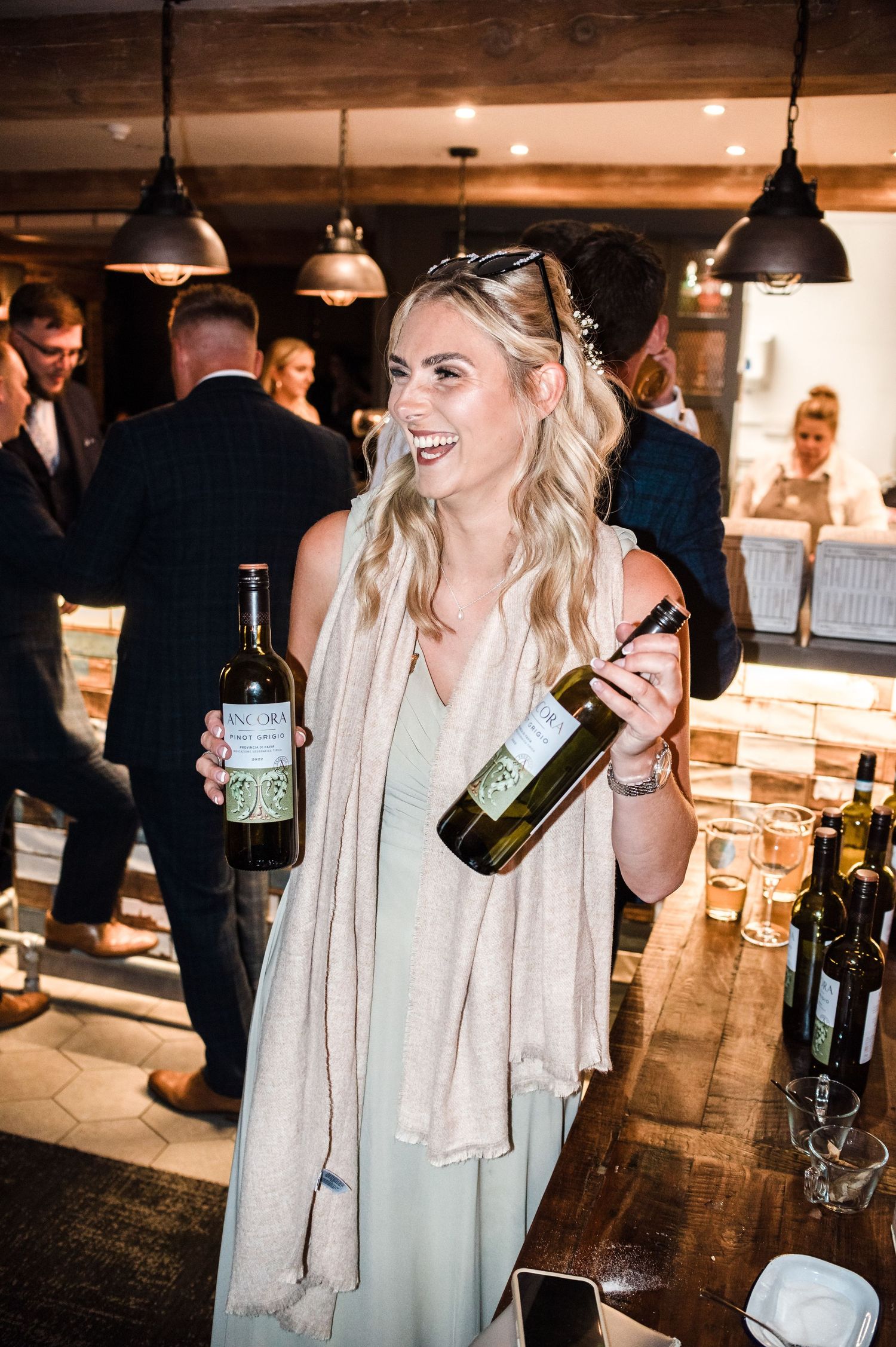 Guest holding wine bottles while celebrating at rustic wedding reception.