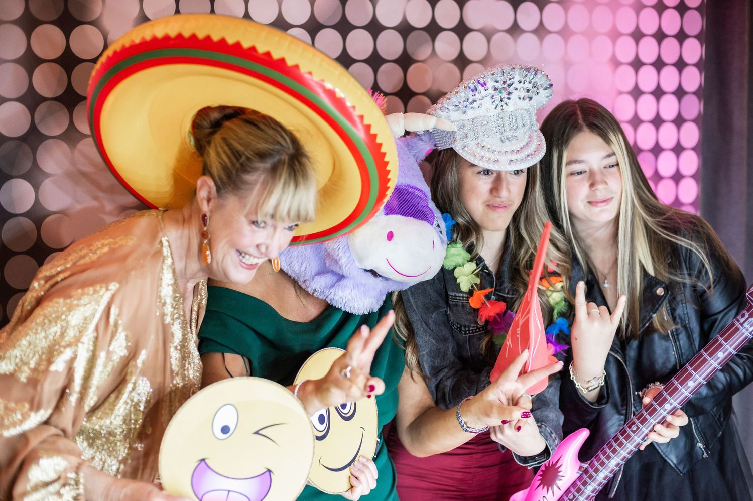 Party guests in costumes posing with props and inflatable instruments against a spotted backdrop.