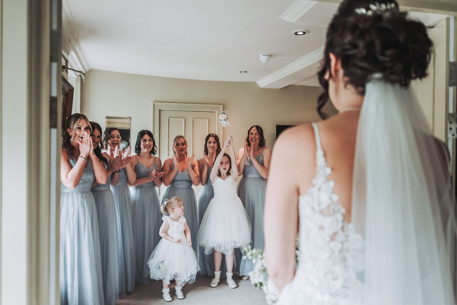 Bridesmaids in pale blue dresses react emotionally to seeing the wedding preparations.
