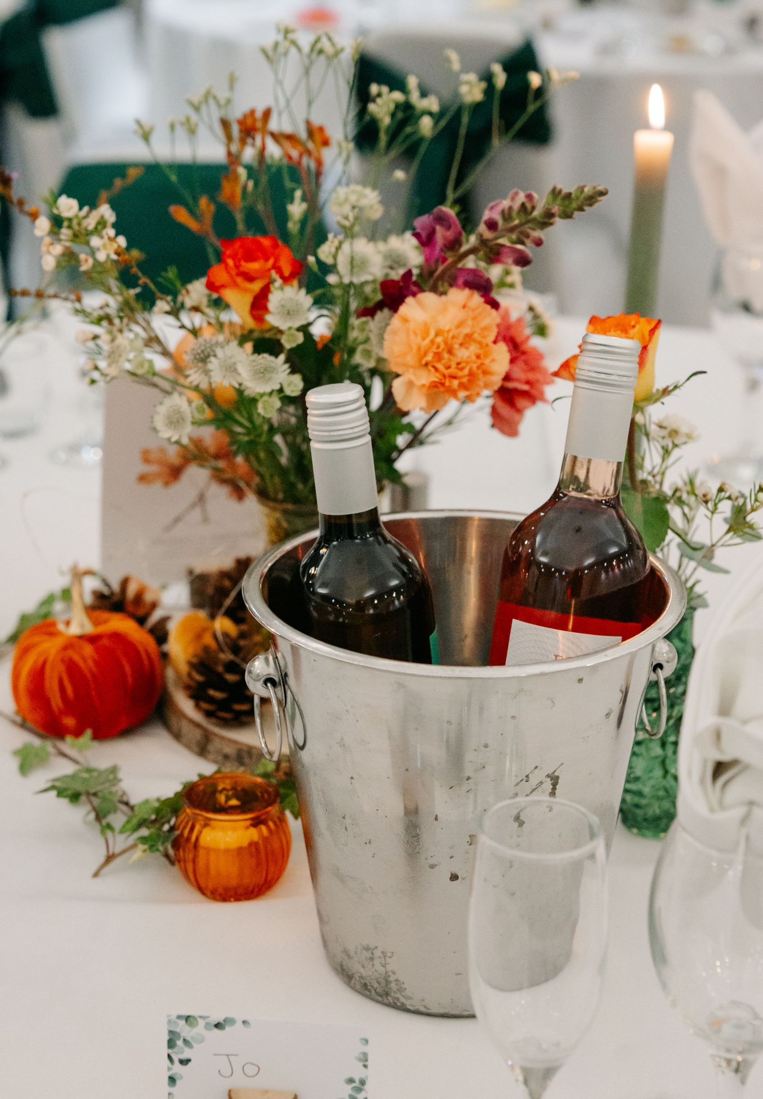Elegant fall wedding table with pumpkin decor, floral arrangements and wine chilling in silver buckets.