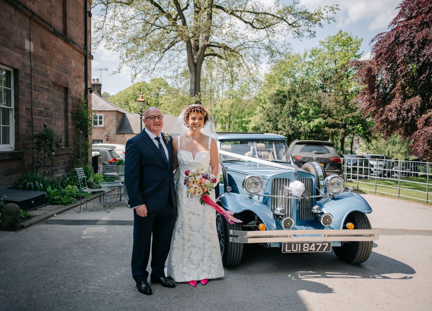 A classic blue vintage car parked outside during a wedding celebration.