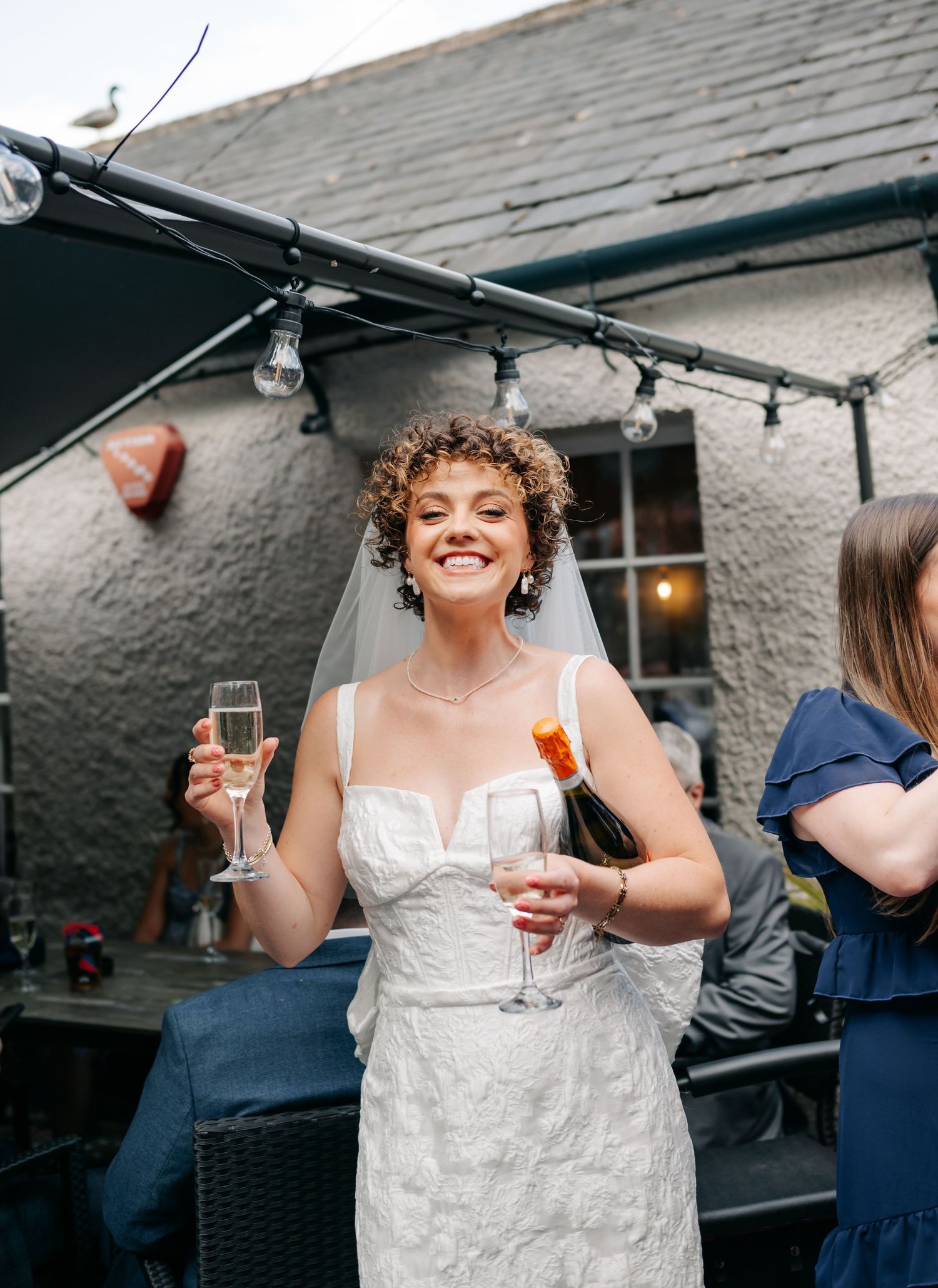 Wedding celebration at a rustic venue with white stone walls and string lights overhead.