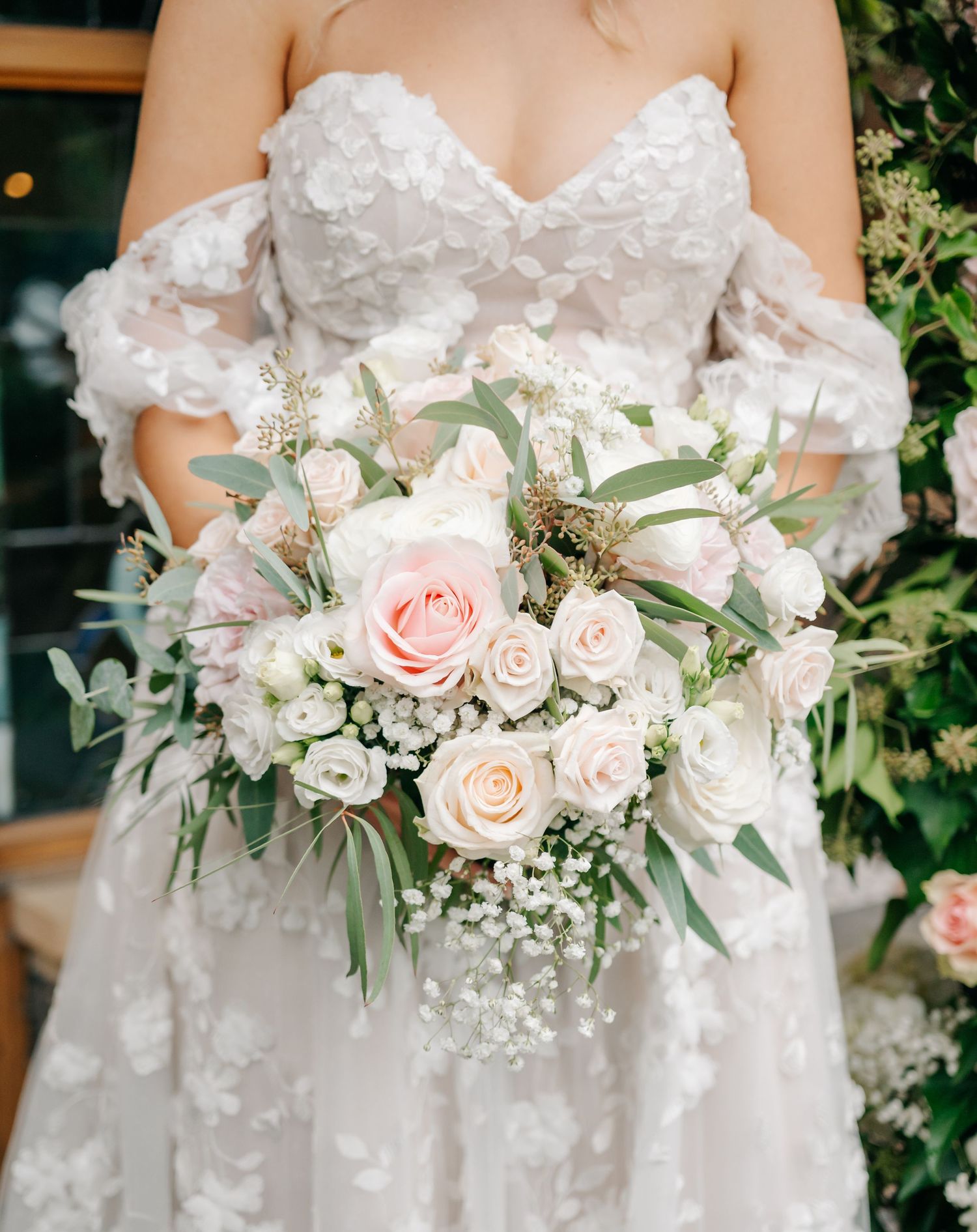 Close-up of bridal bouquet featuring blush roses, white flowers, and eucalyptus leaves.