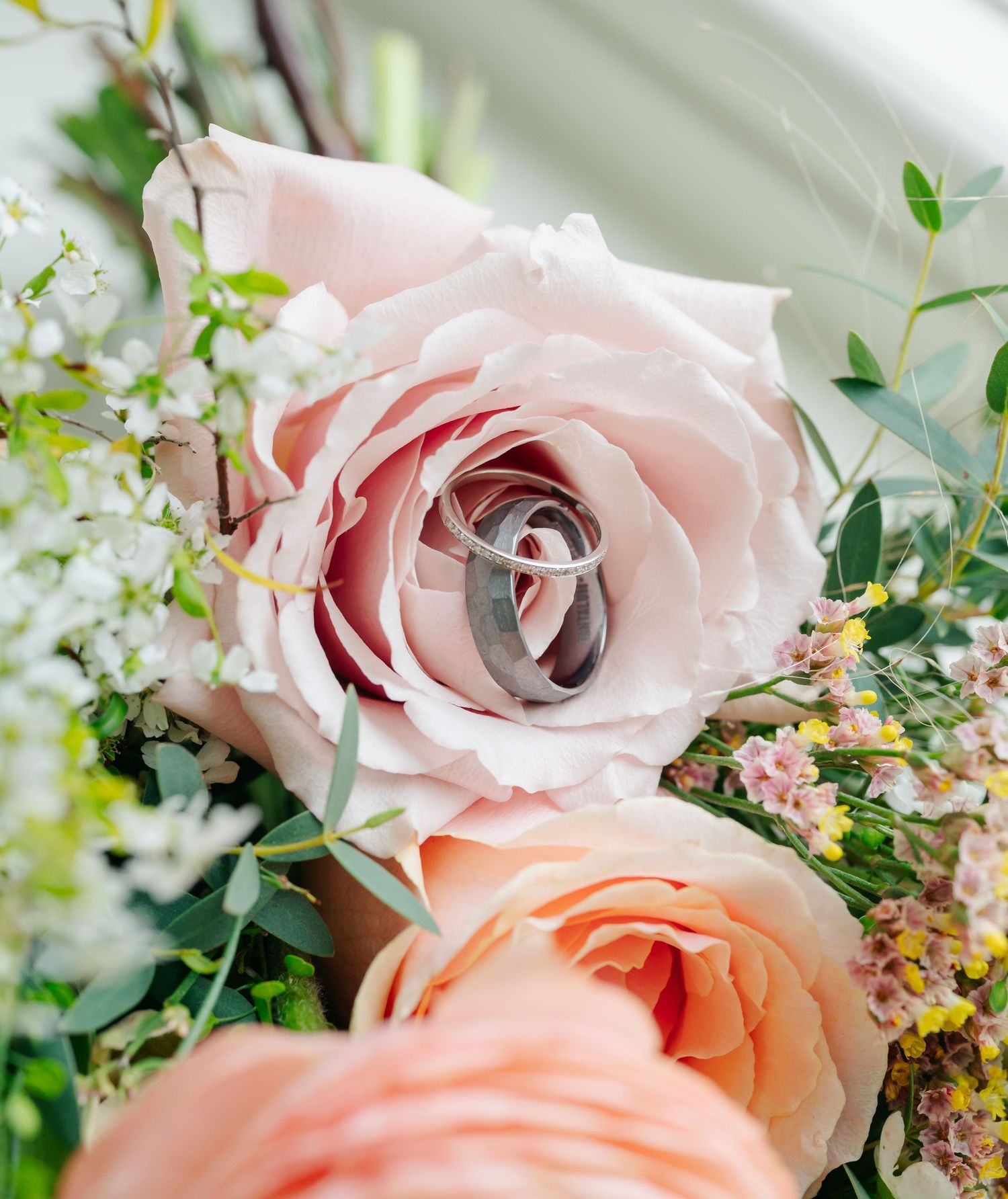 Delicate pink and peach roses arranged with greenery in a romantic floral display.