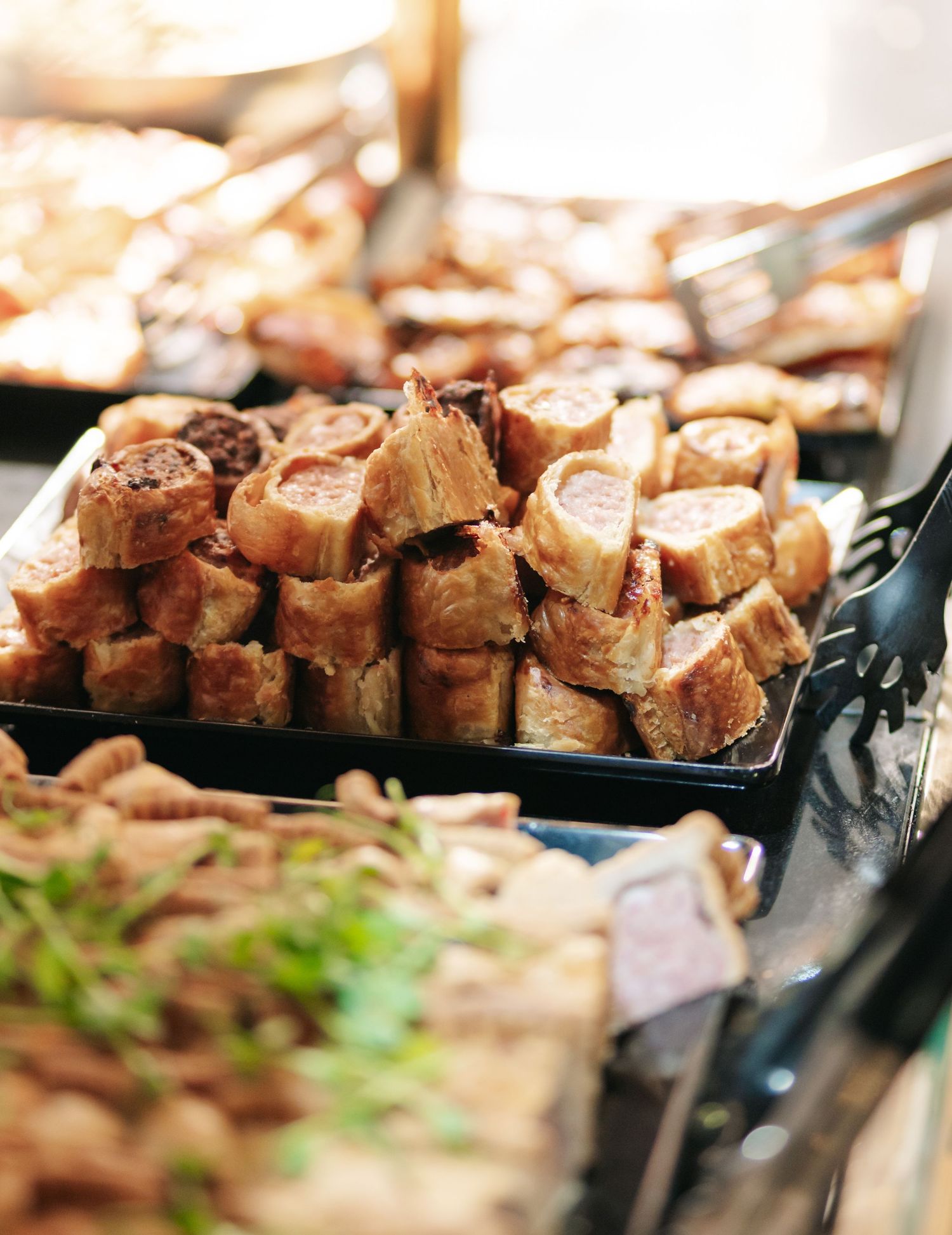 Close-up of roasted meat chunks arranged on black serving platters at a catering event.