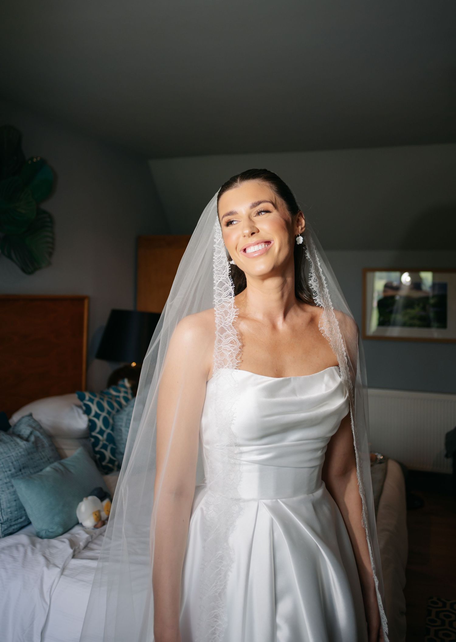 A bride in a classic white wedding dress and veil poses in a series of candid getting ready shots.