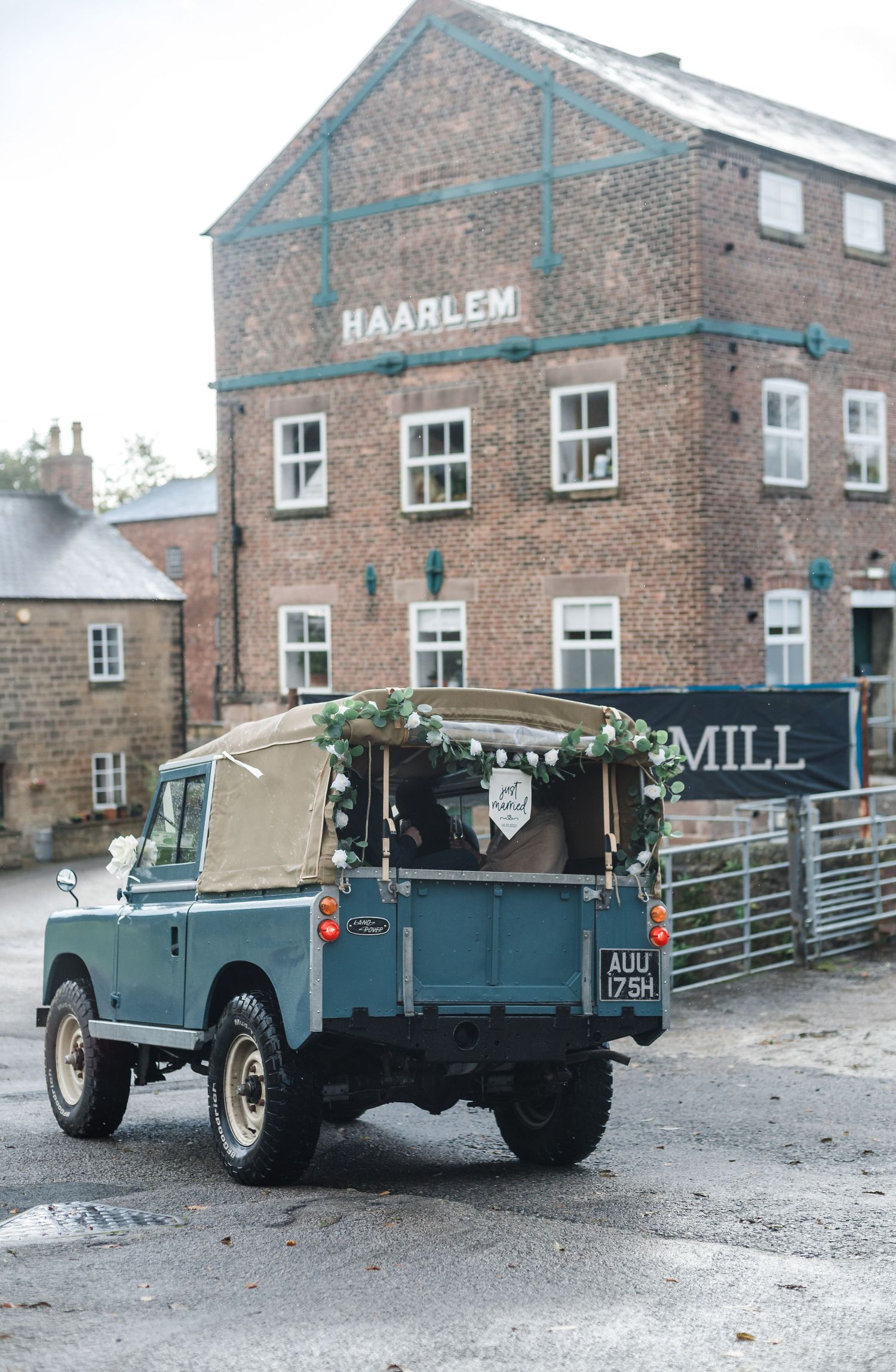 Vintage blue Land Rover parked outside historic Haarlem Mill brick building.