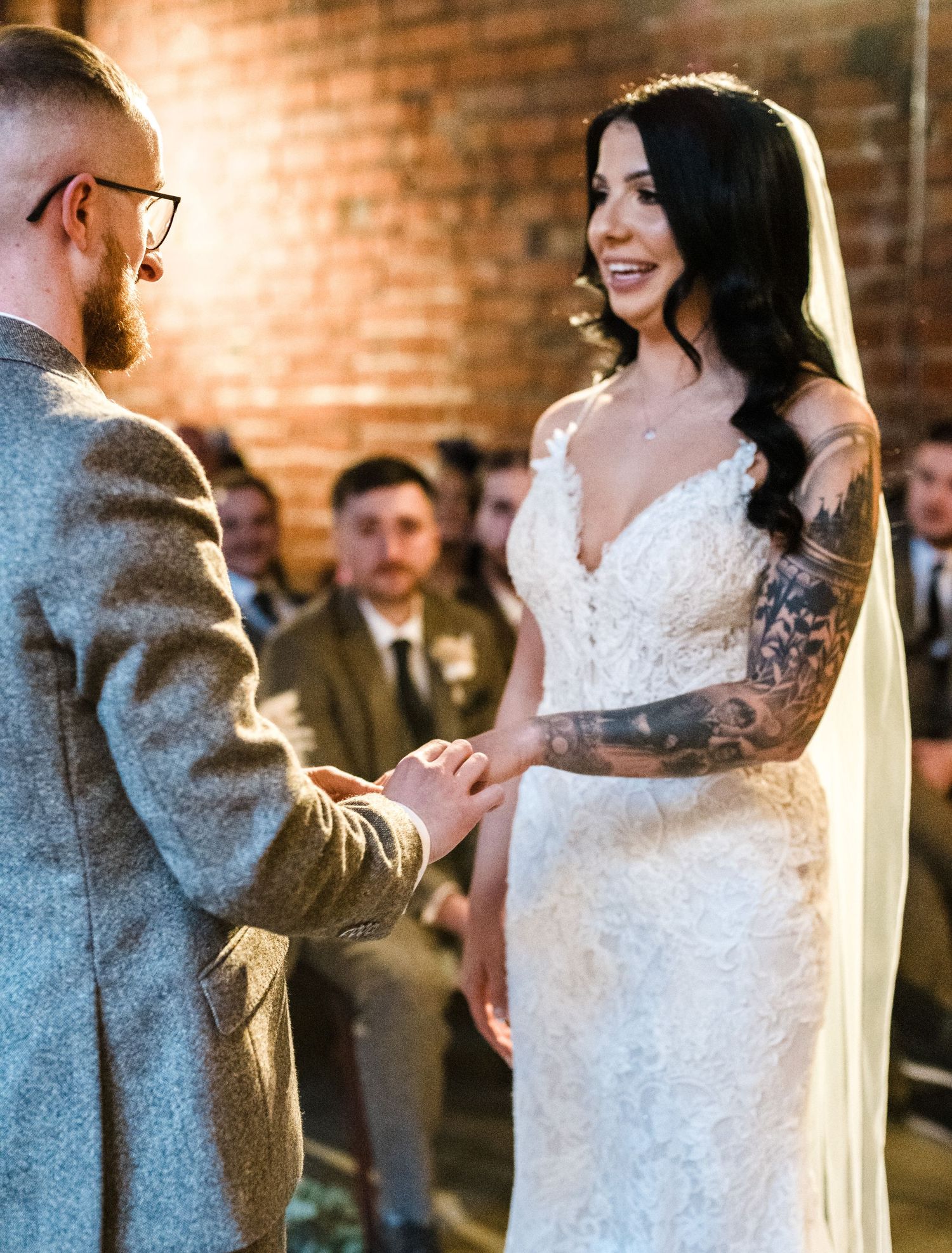 A couple exchanges rings during an intimate brick-walled ceremony.
