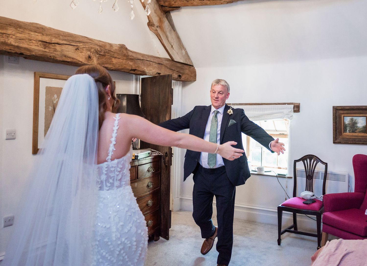 Wedding scene of dancing in bright room with exposed wooden beams.