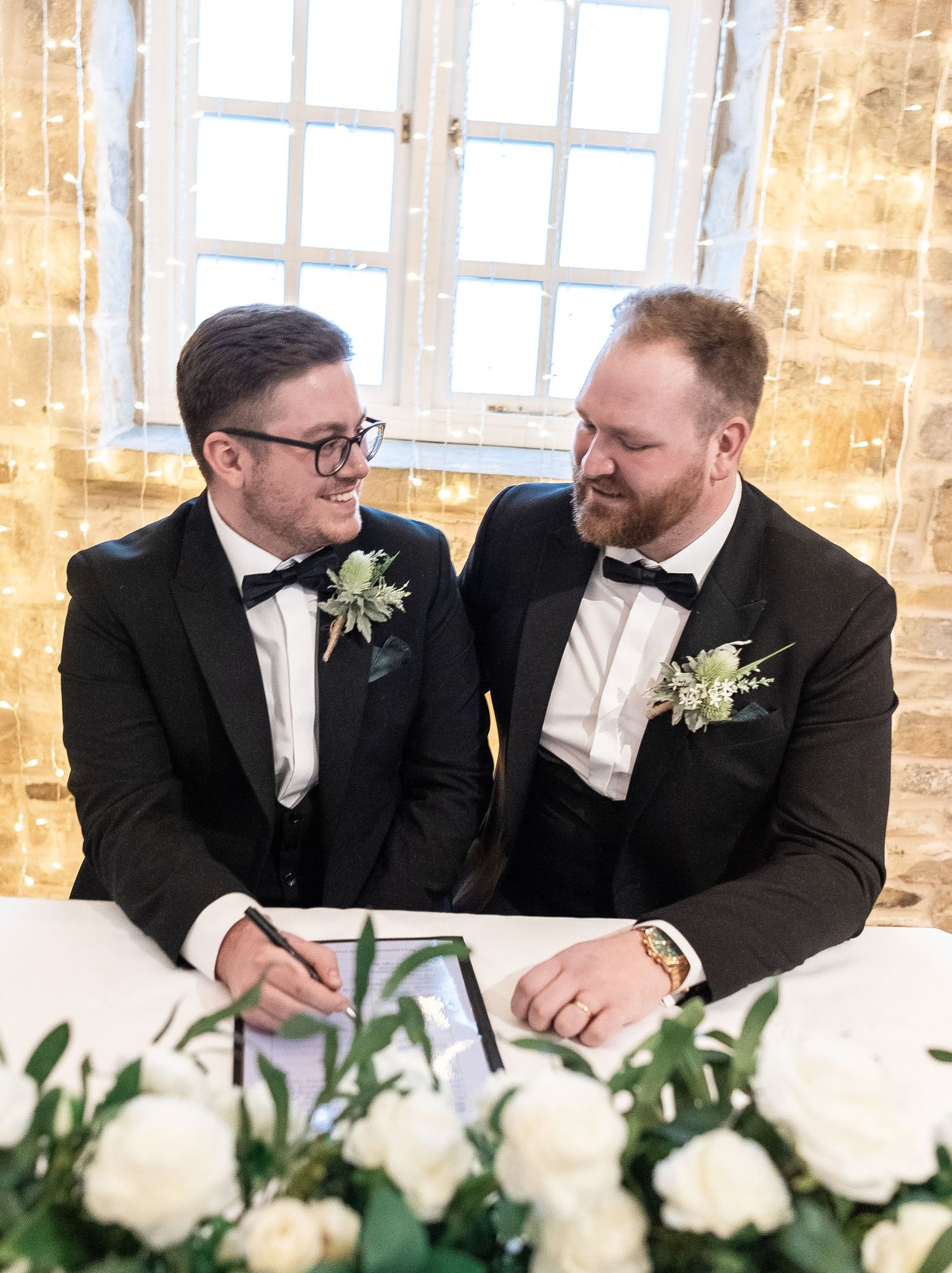 Couple sharing intimate moment at signing table decorated with white roses.