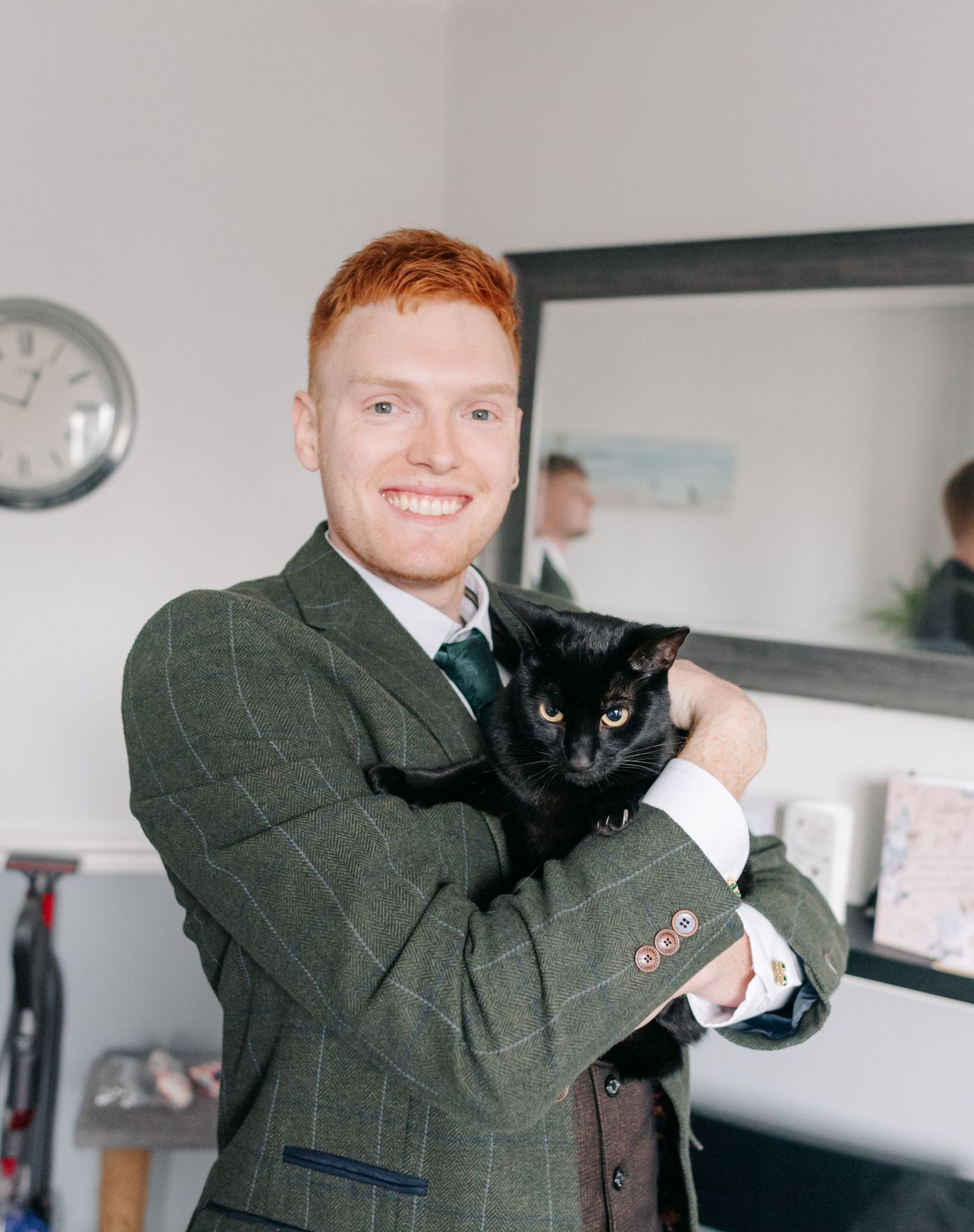 Wedding party member in a dark suit holding a playful black cat.
