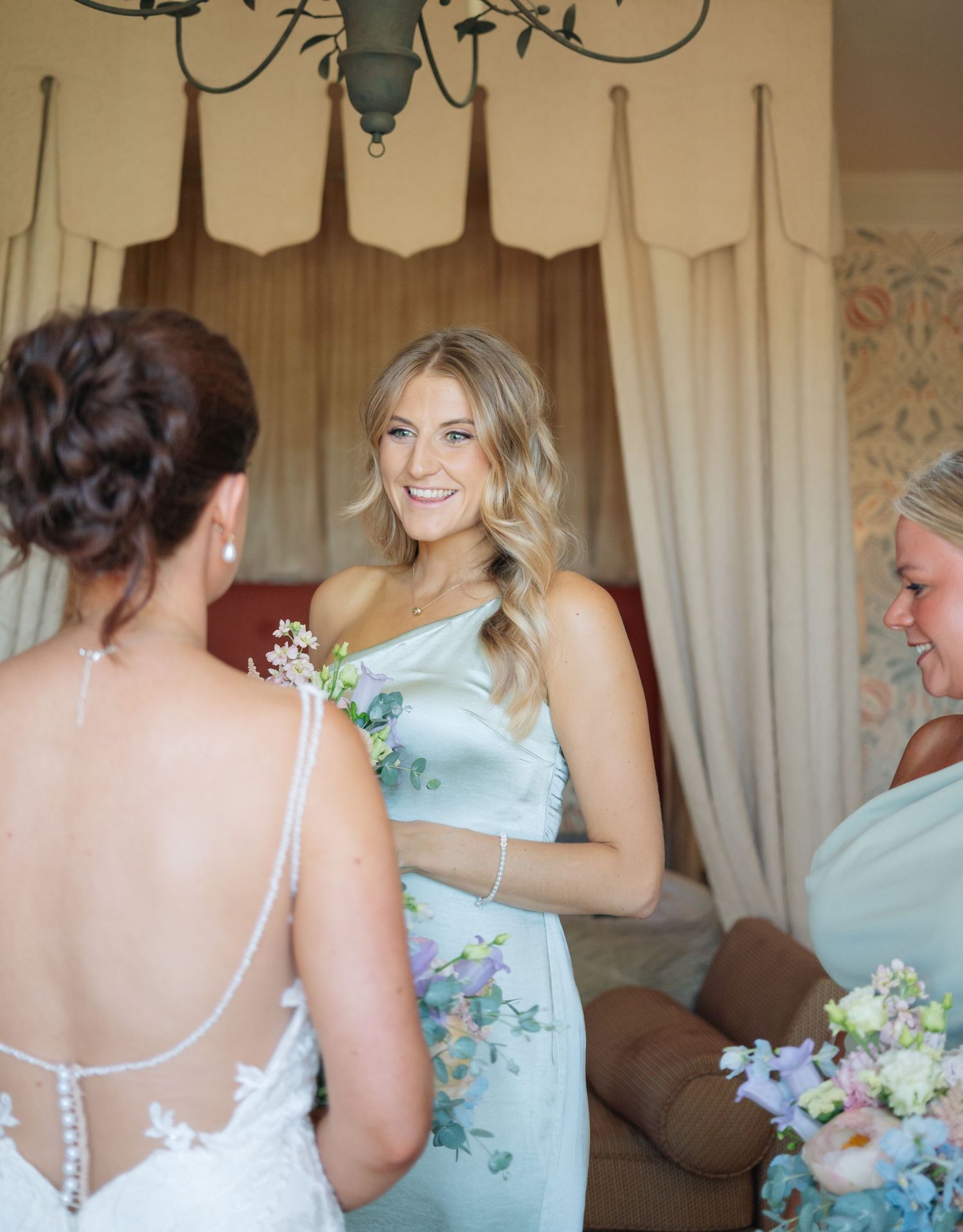 Bridesmaids in mint green dresses helping with wedding preparations indoors.