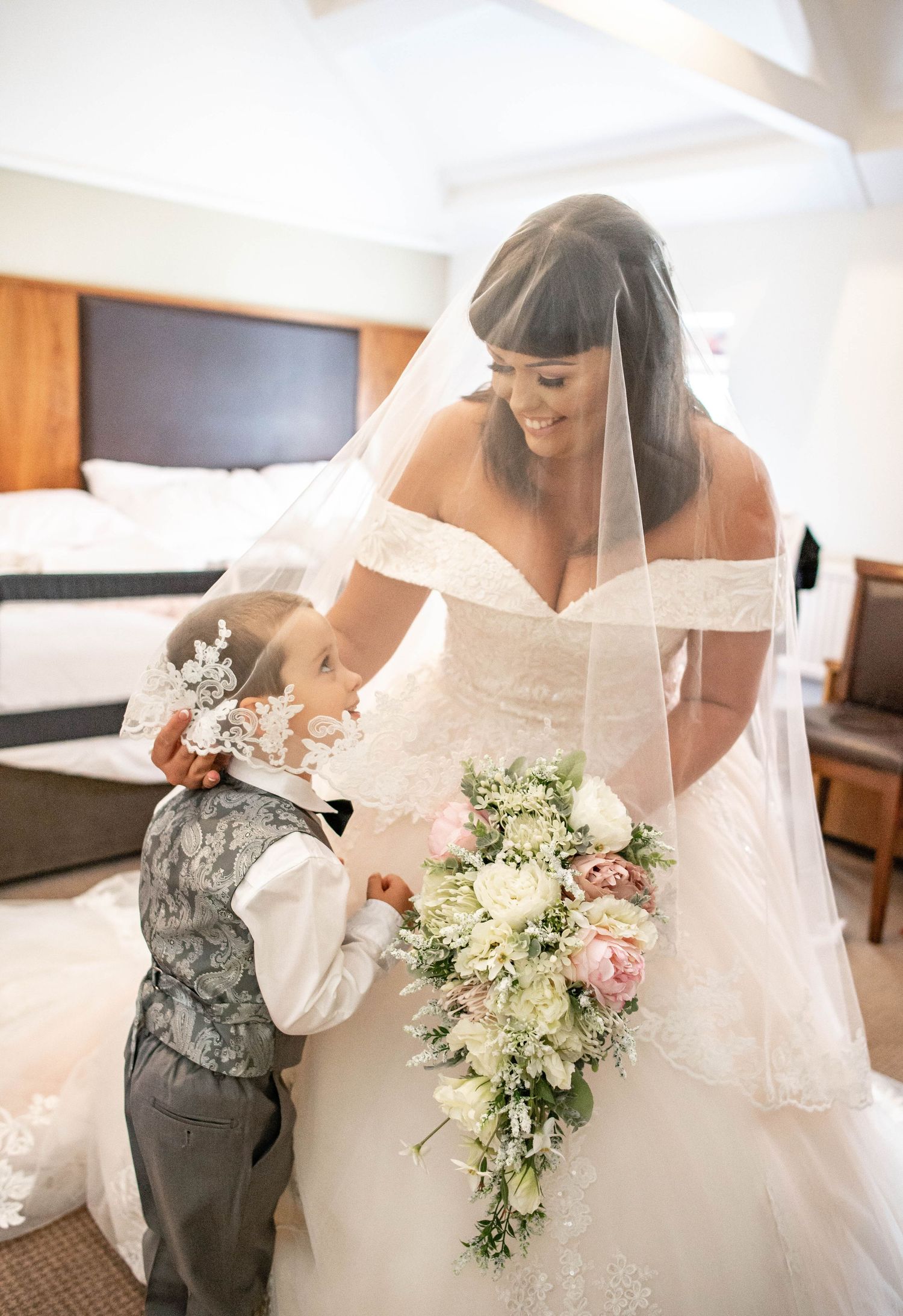 A tender wedding moment captured in a hotel room with a bridal bouquet.