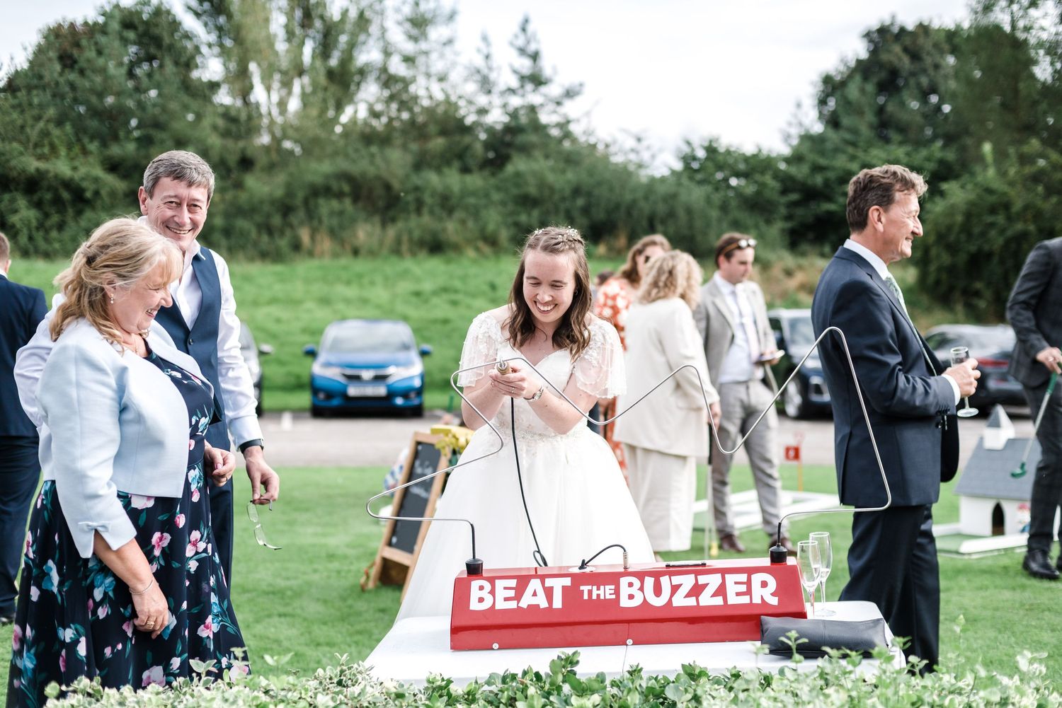 Group playing Beat the Buzzer game during outdoor wedding reception on sunny day.