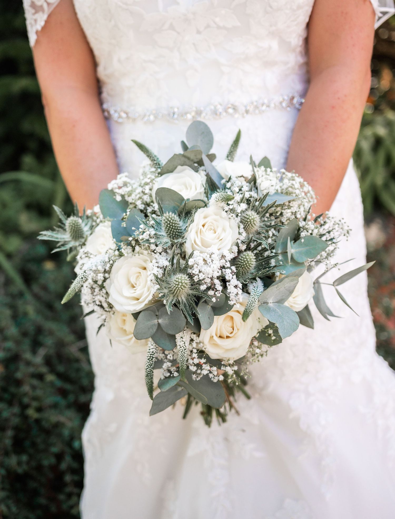 A white and sage green wedding bouquet with roses, eucalyptus, and baby's breath.