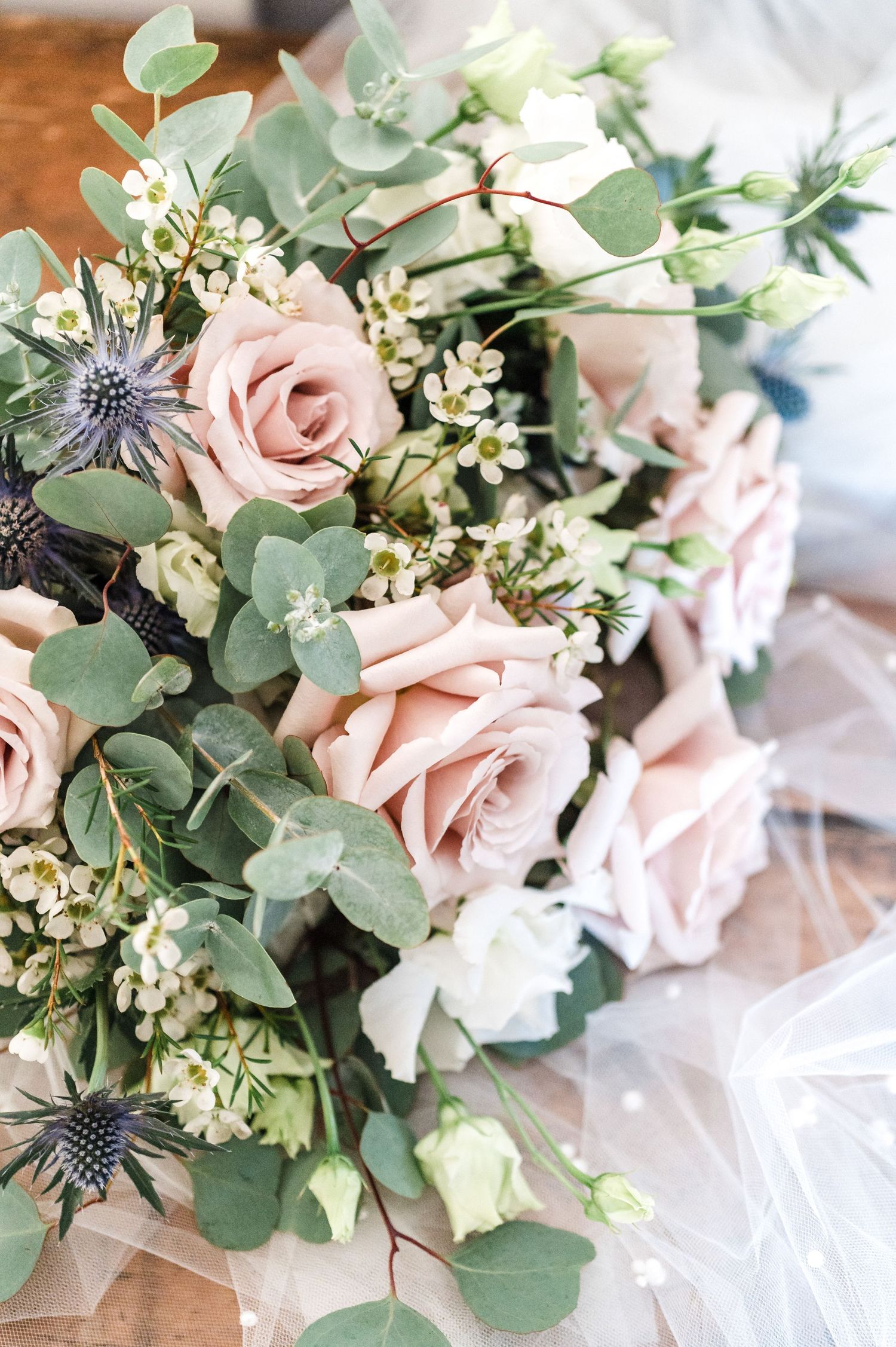 Elegant bridal bouquet featuring pink roses, eucalyptus, and blue thistles.