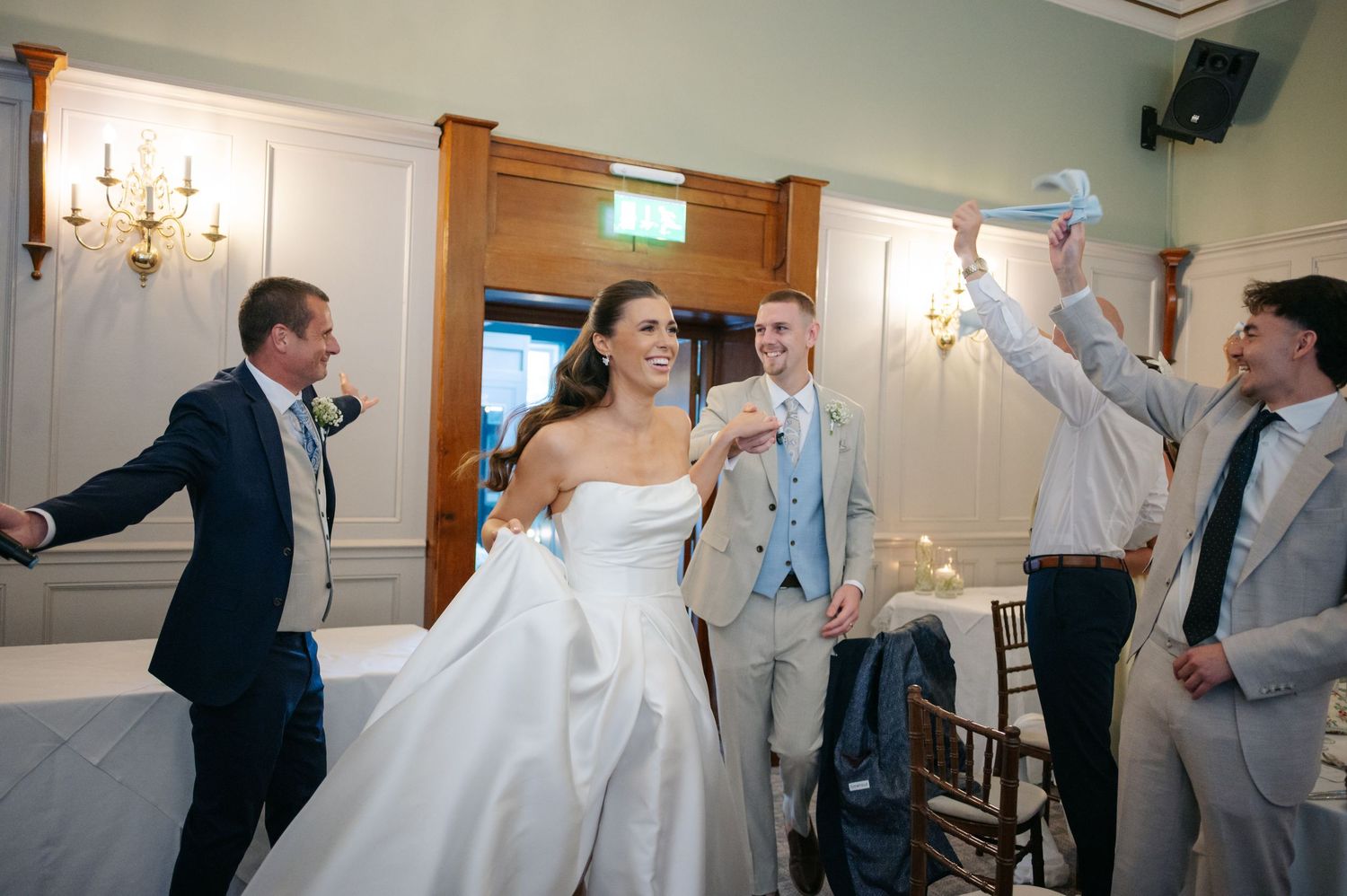 Wedding party members dancing and celebrating during a reception in an elegant ballroom.