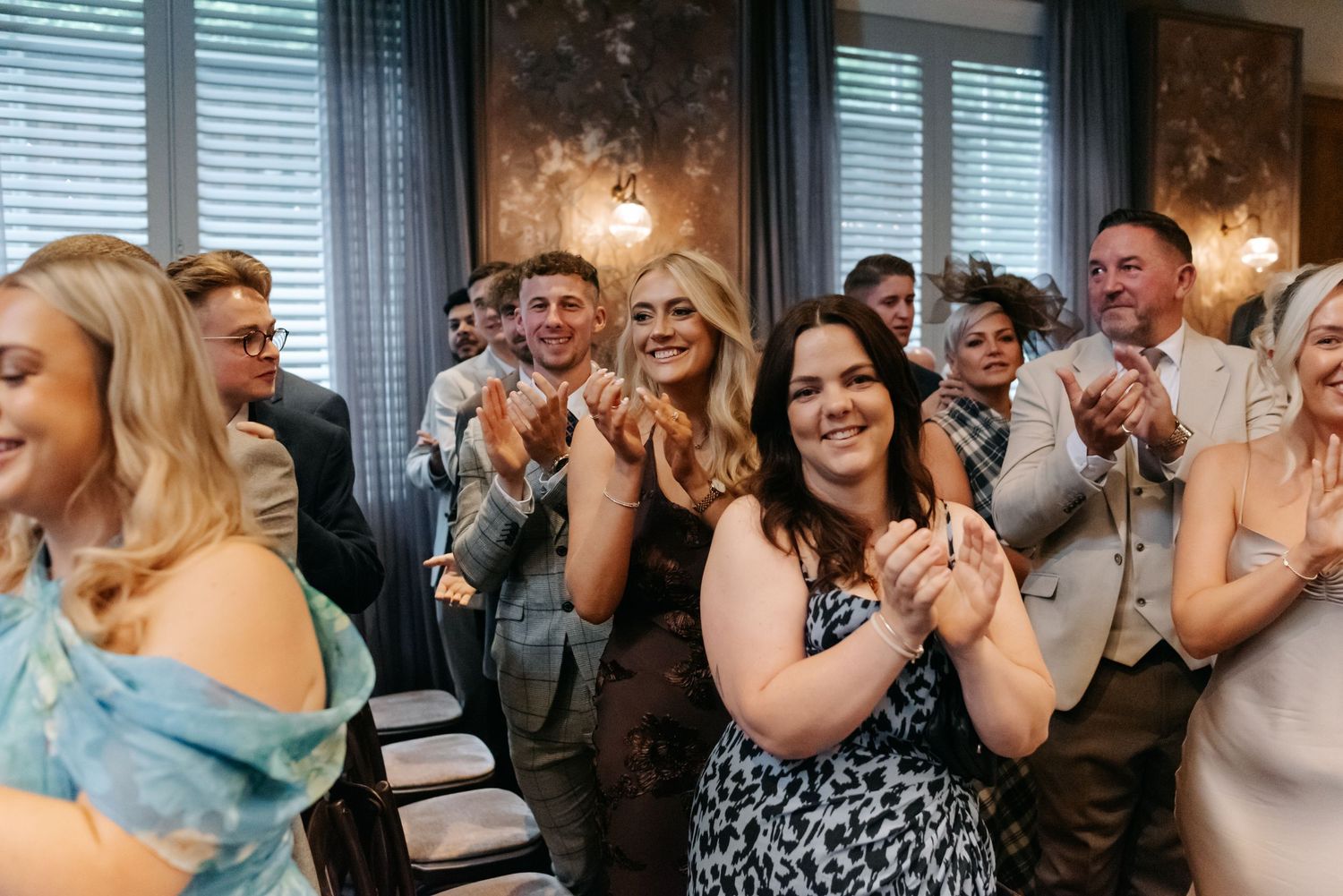 Wedding guests react with joy and applause during an emotional celebration moment.