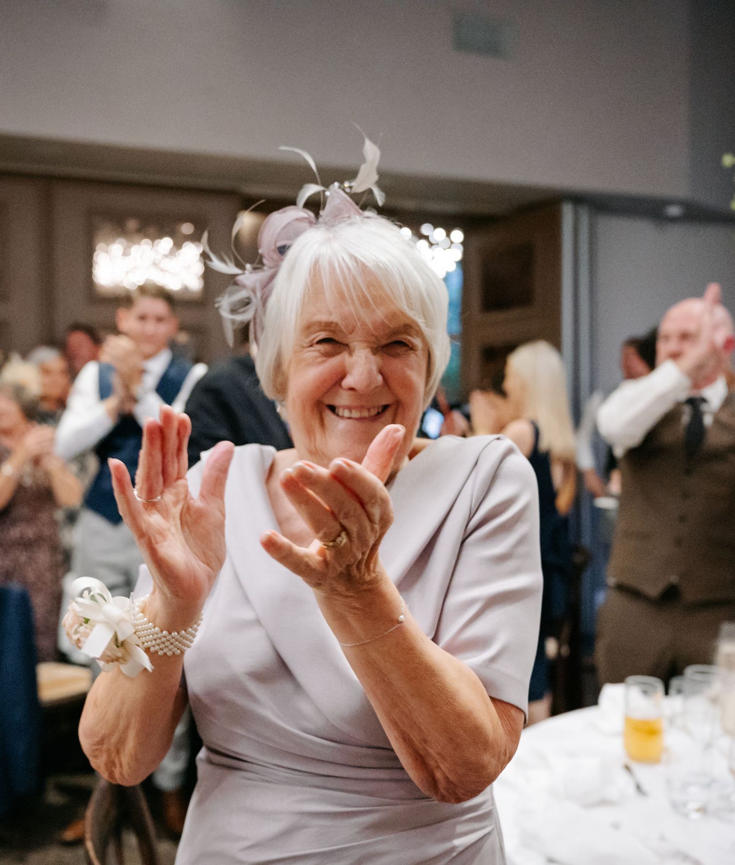 A person in white attire laughs joyfully during what appears to be a celebratory event or gathering.