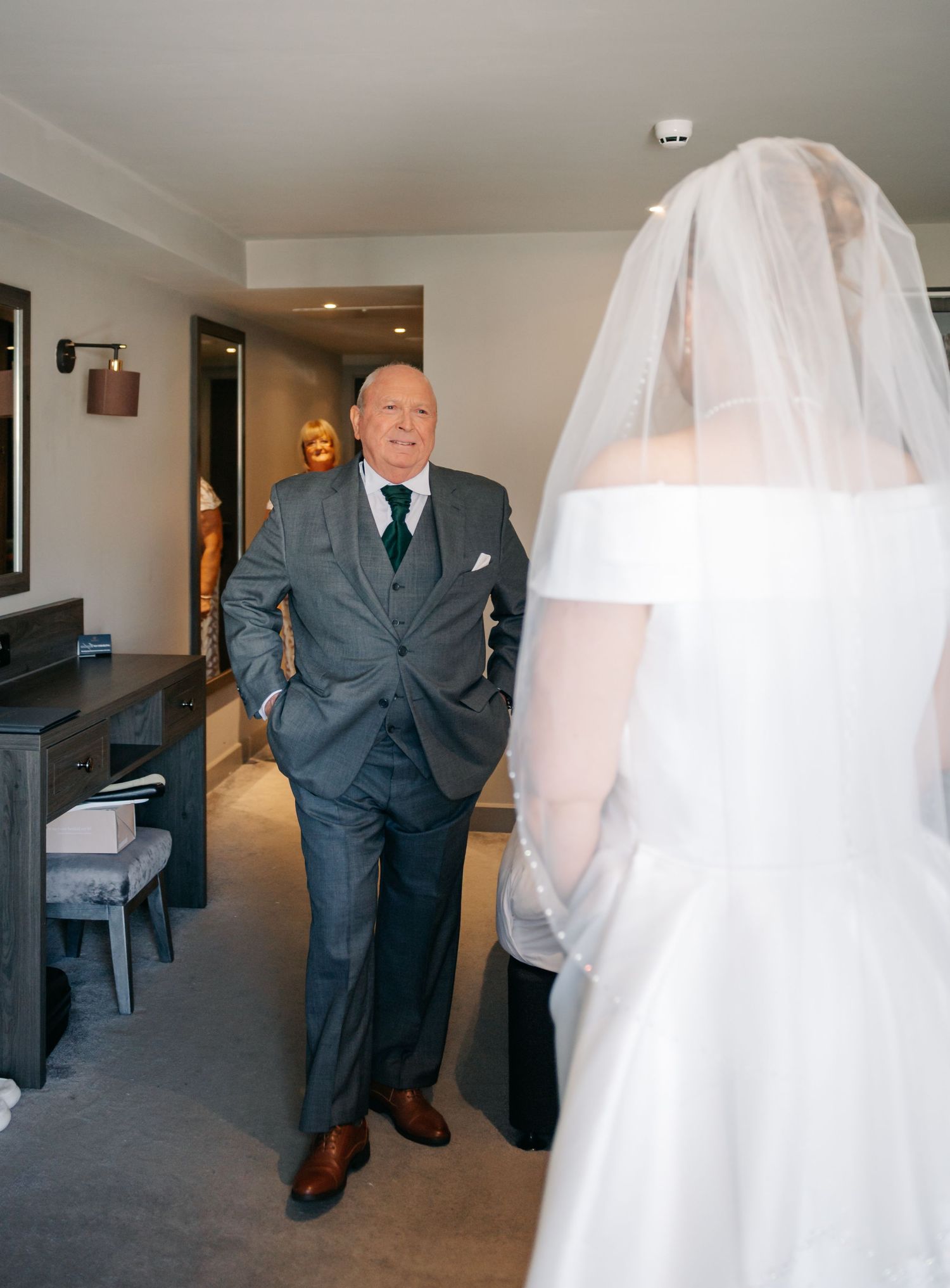 Wedding scene in a hotel hallway with a bride in white and someone in a gray suit.