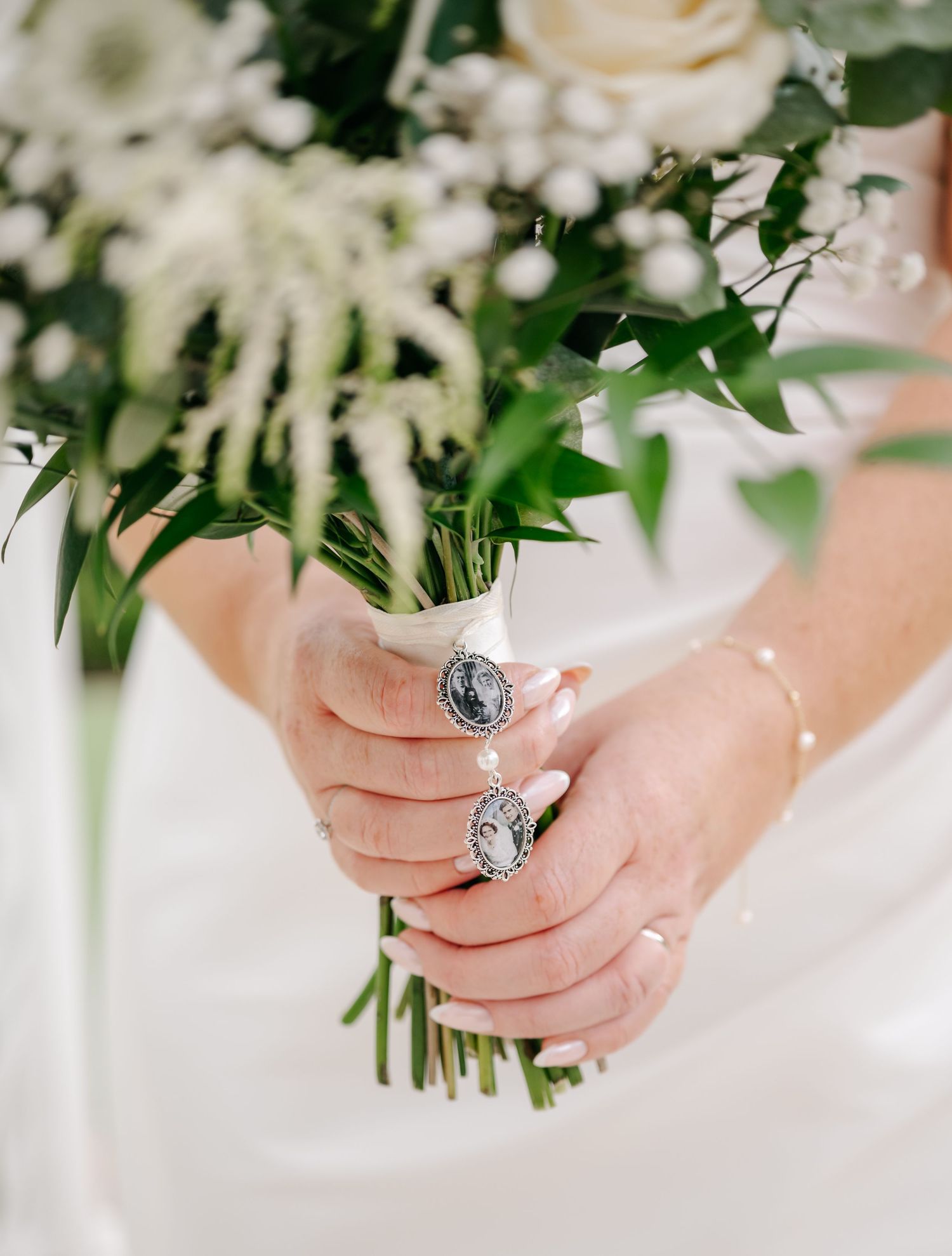 Close-up of bridal hands holding white floral bouquet with vintage ring detail.