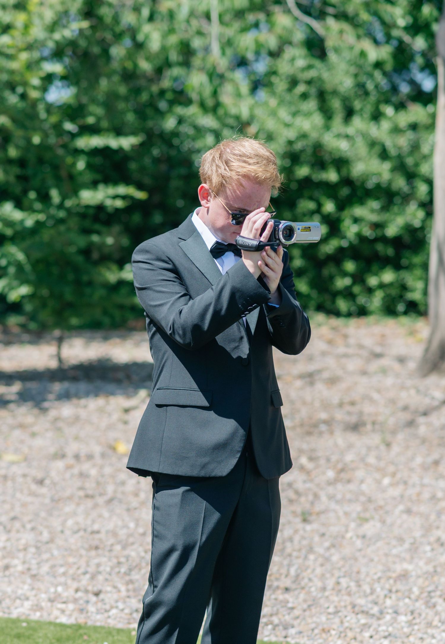 Sequence of groomsmen taking photos outdoors in dark suits.