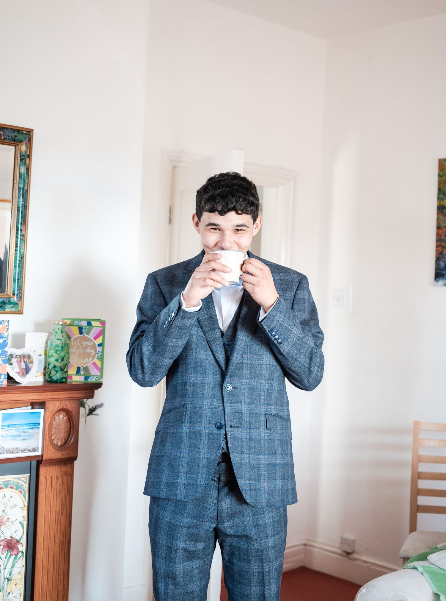 A sequence of playful poses in a blue checkered suit against a white interior wall.