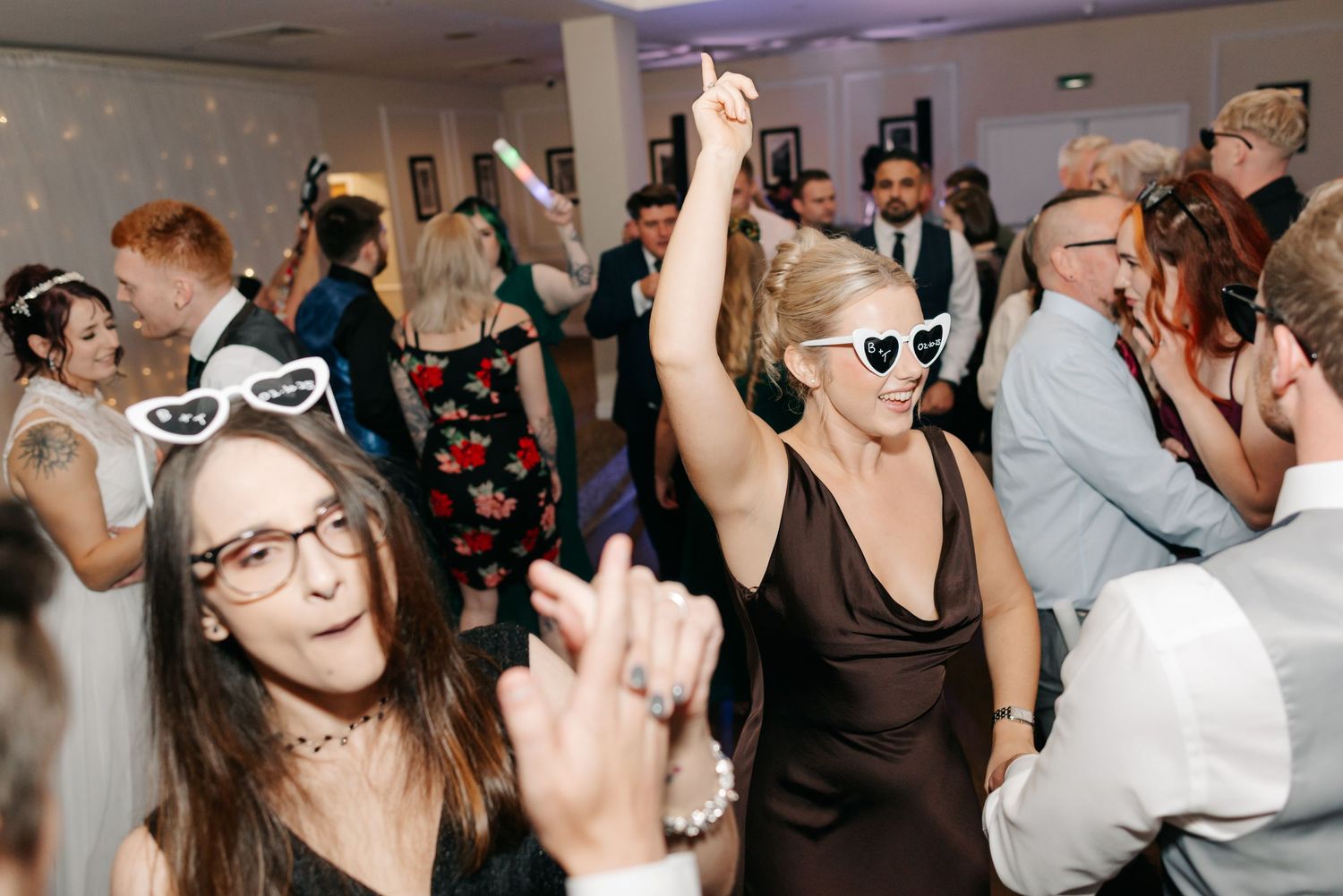 Energetic wedding reception dance party with guests celebrating on the dance floor.