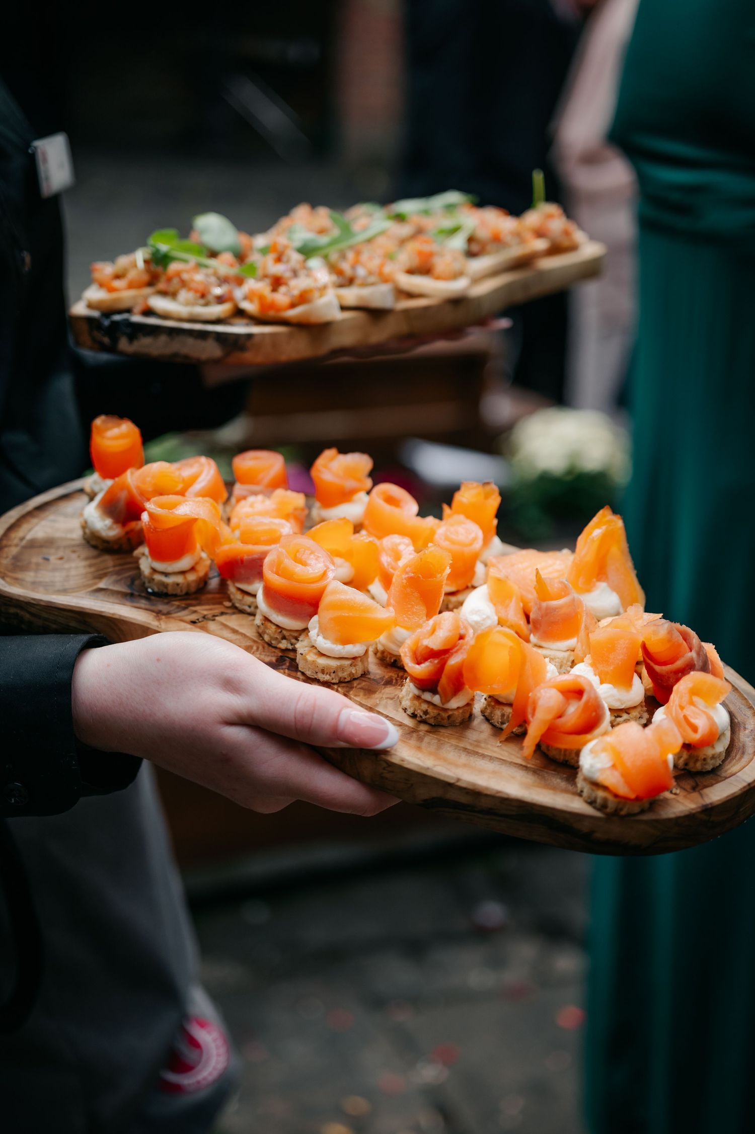 Wooden serving board with smoked salmon canapés being presented at an elegant event.