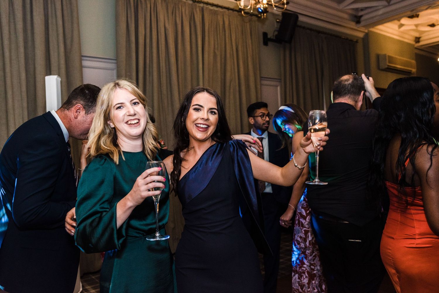 Guests laughing and enjoying drinks at an elegant indoor celebration.
