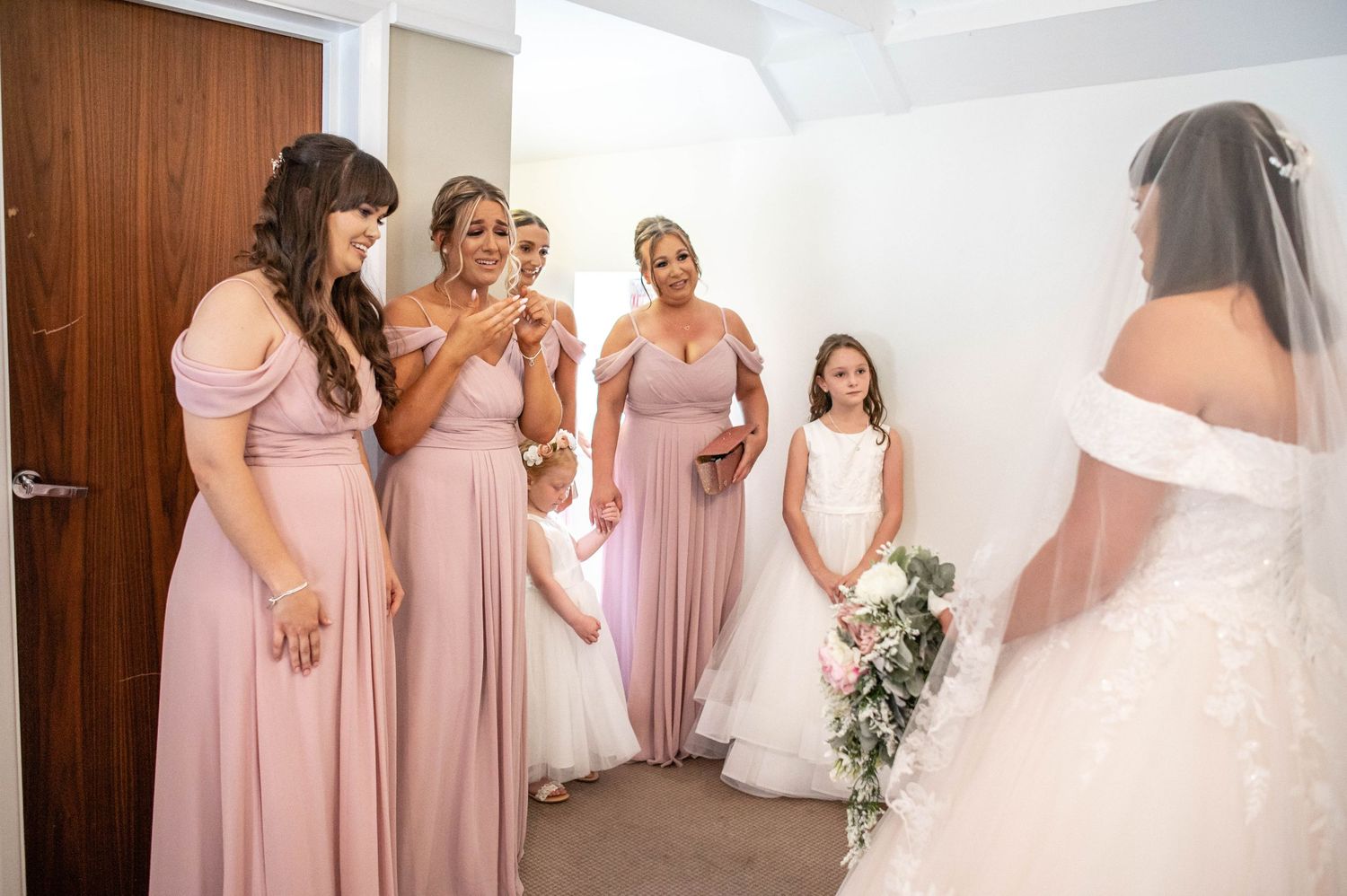 Bridesmaids in pink dresses share a special moment before the ceremony.