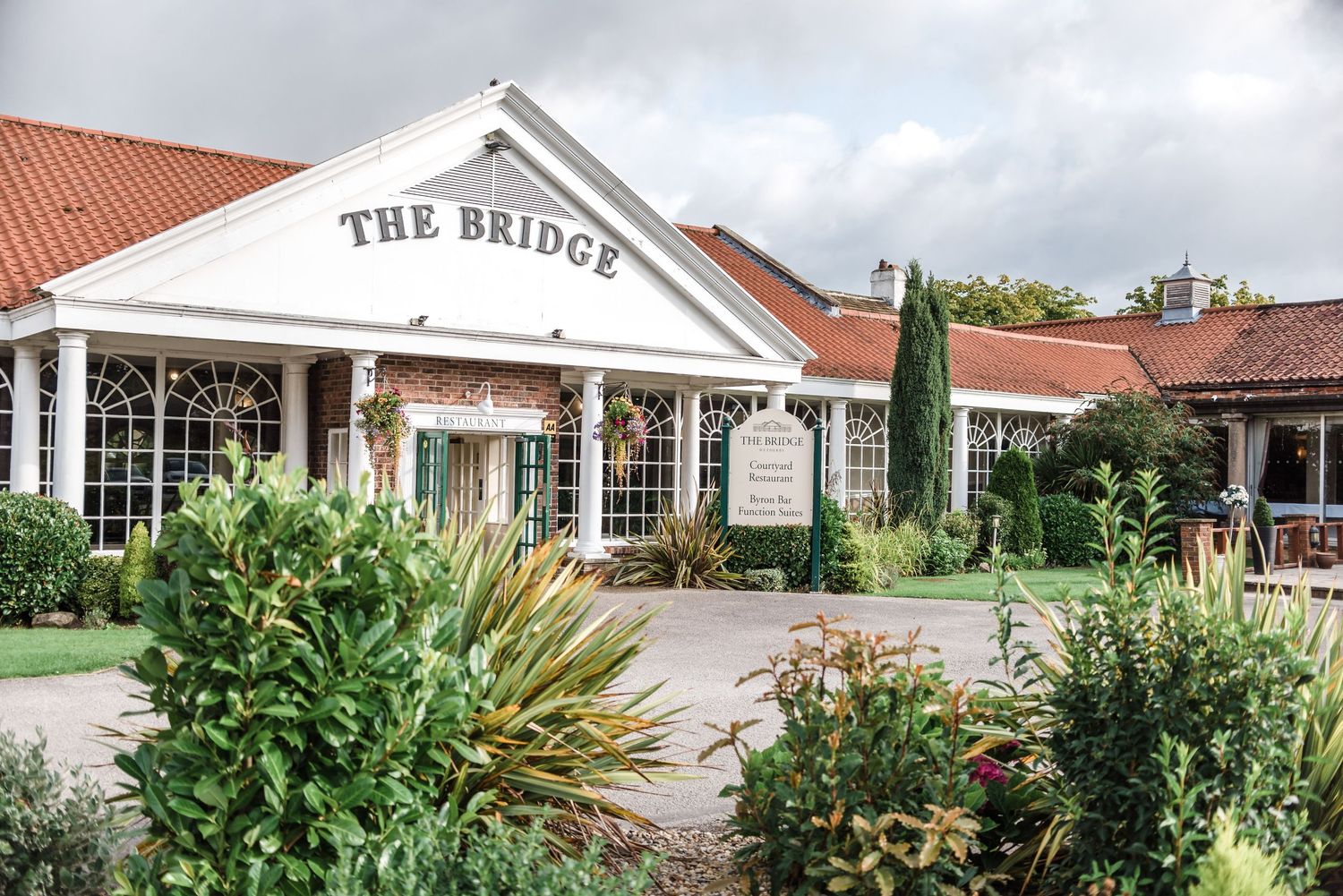 Exterior view of The Bridge venue with landscaped garden entrance.