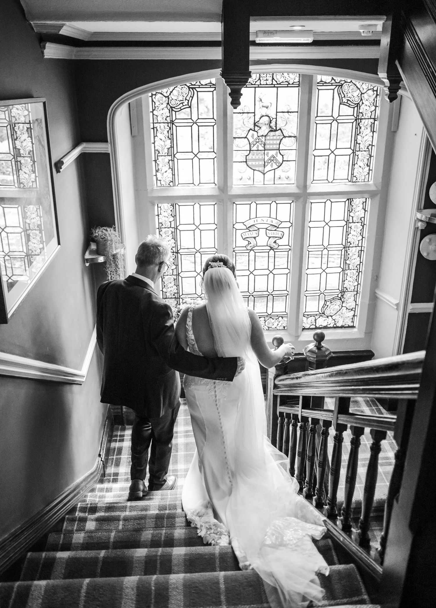 Black and white photos of couple ascending staircase with stained glass windows.