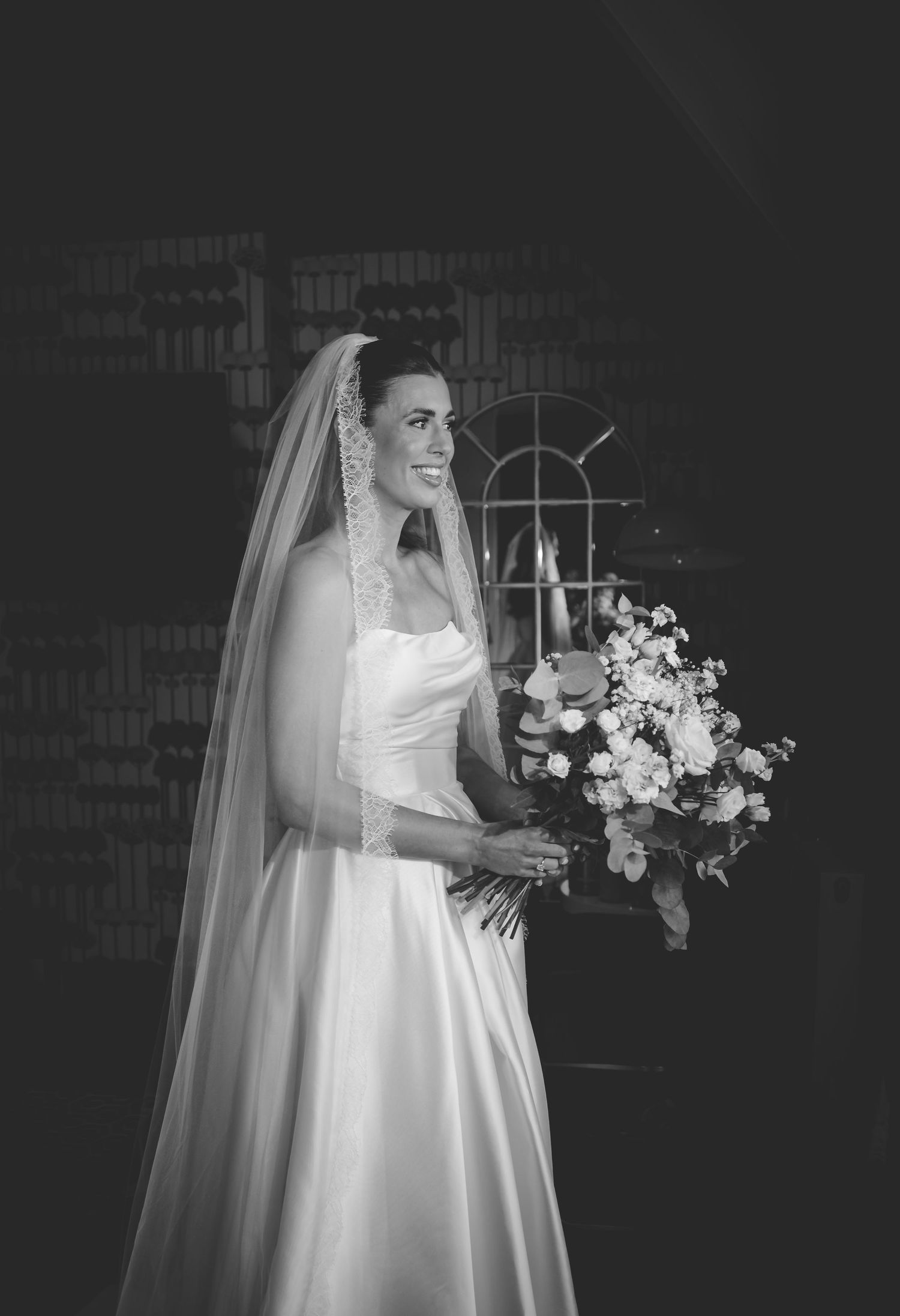 Classic black and white bridal portrait showing a bride in a flowing white dress holding an elegant bouquet.