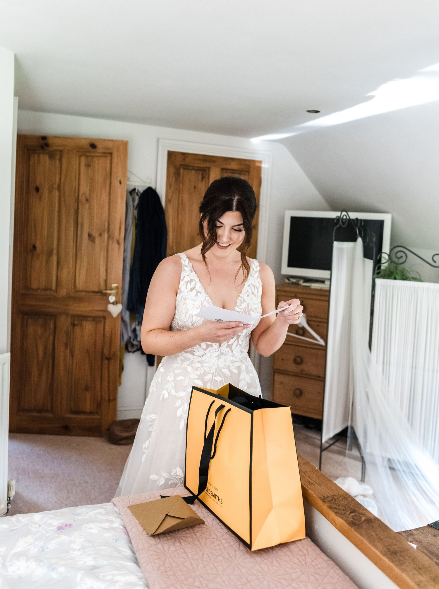 Wedding preparation scene with a person in a white lace dress looking at items in a yellow shopping bag.