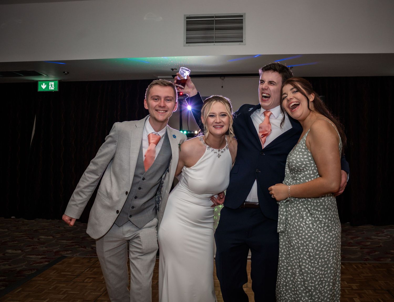 Wedding party poses together at evening reception with decorative lighting.