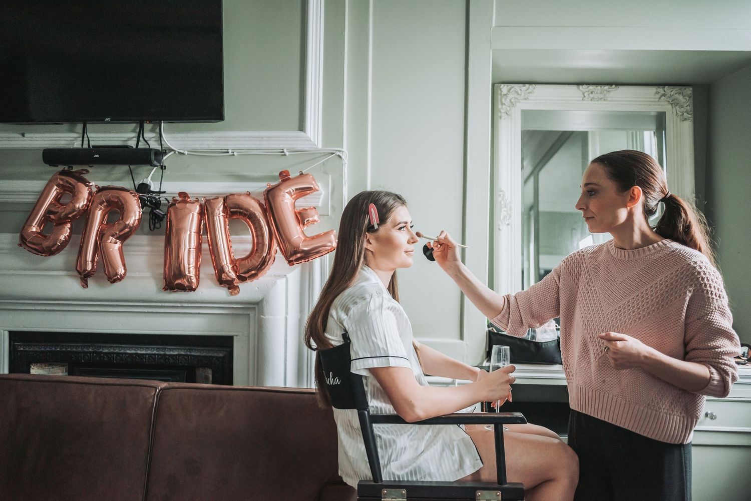 Bridal preparation scene with rose gold 'BRIDE' balloons in the background.