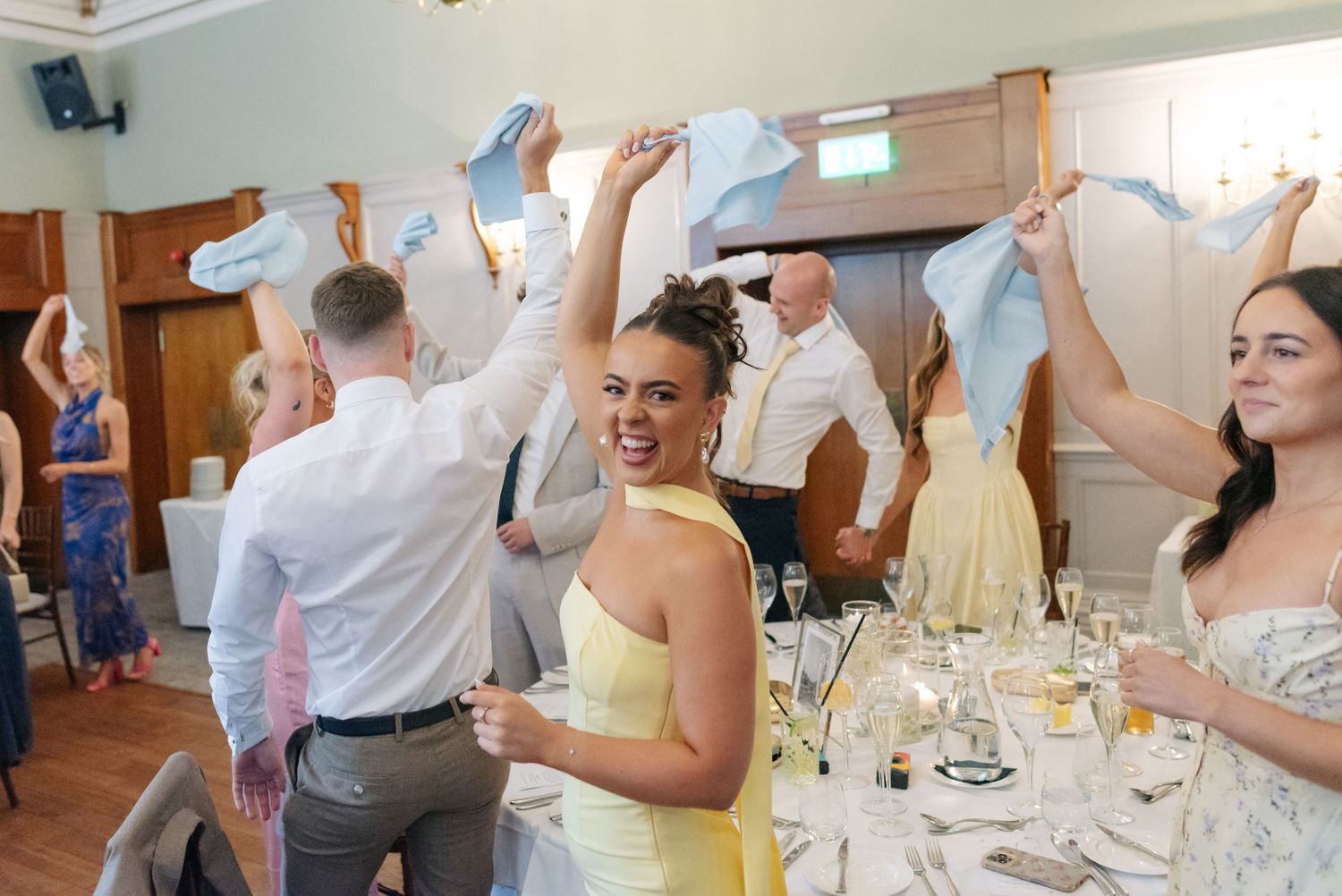Wedding reception guests celebrate with arms raised in joyful celebration.