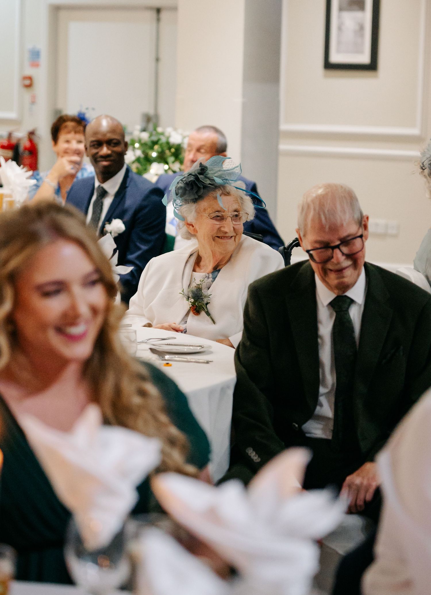 Wedding guests enjoying a reception with elderly attendees sharing joyful moments.