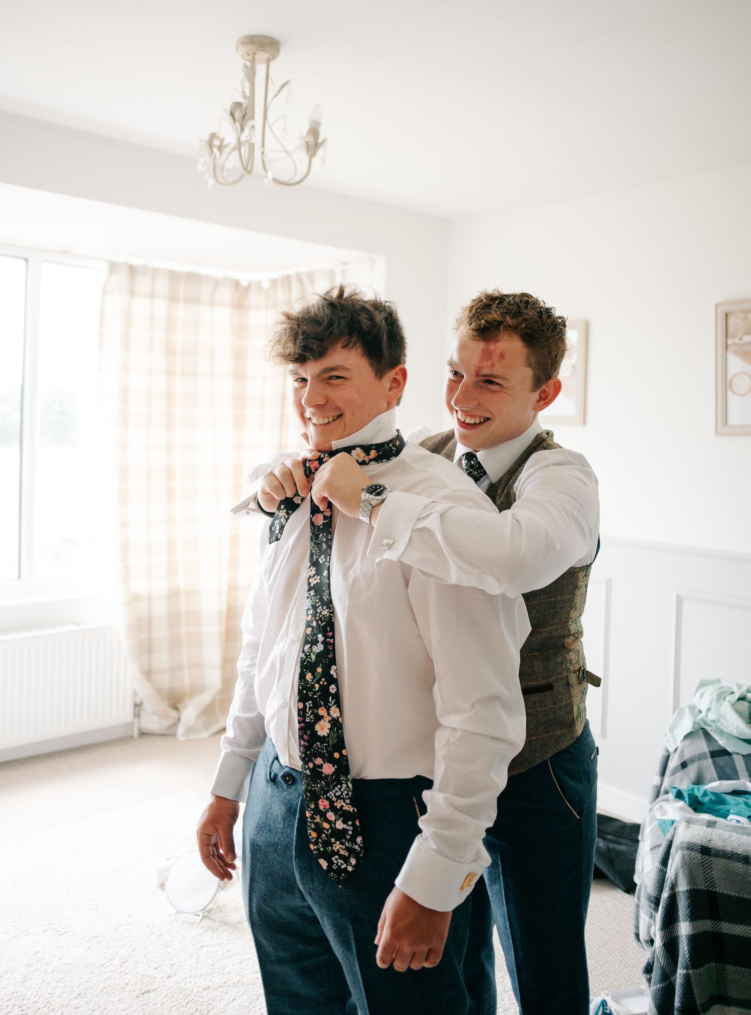 Wedding party members in formal attire helping each other get ready.
