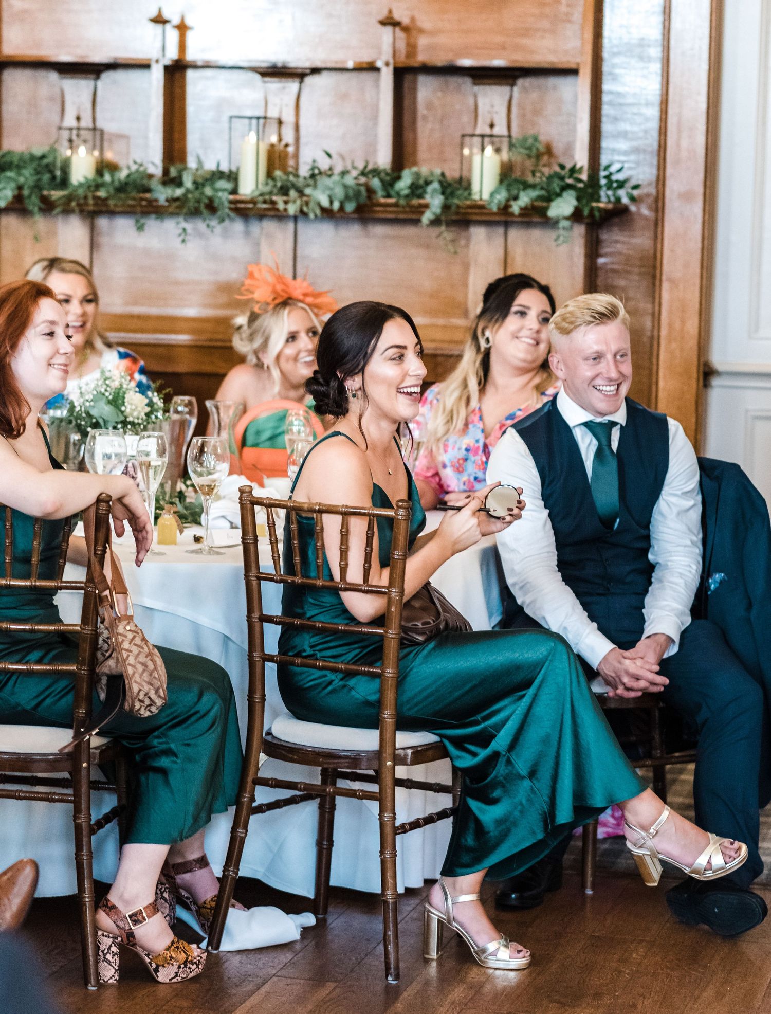 Wedding guests seated at elegant table with emerald green dresses and floral decorations.