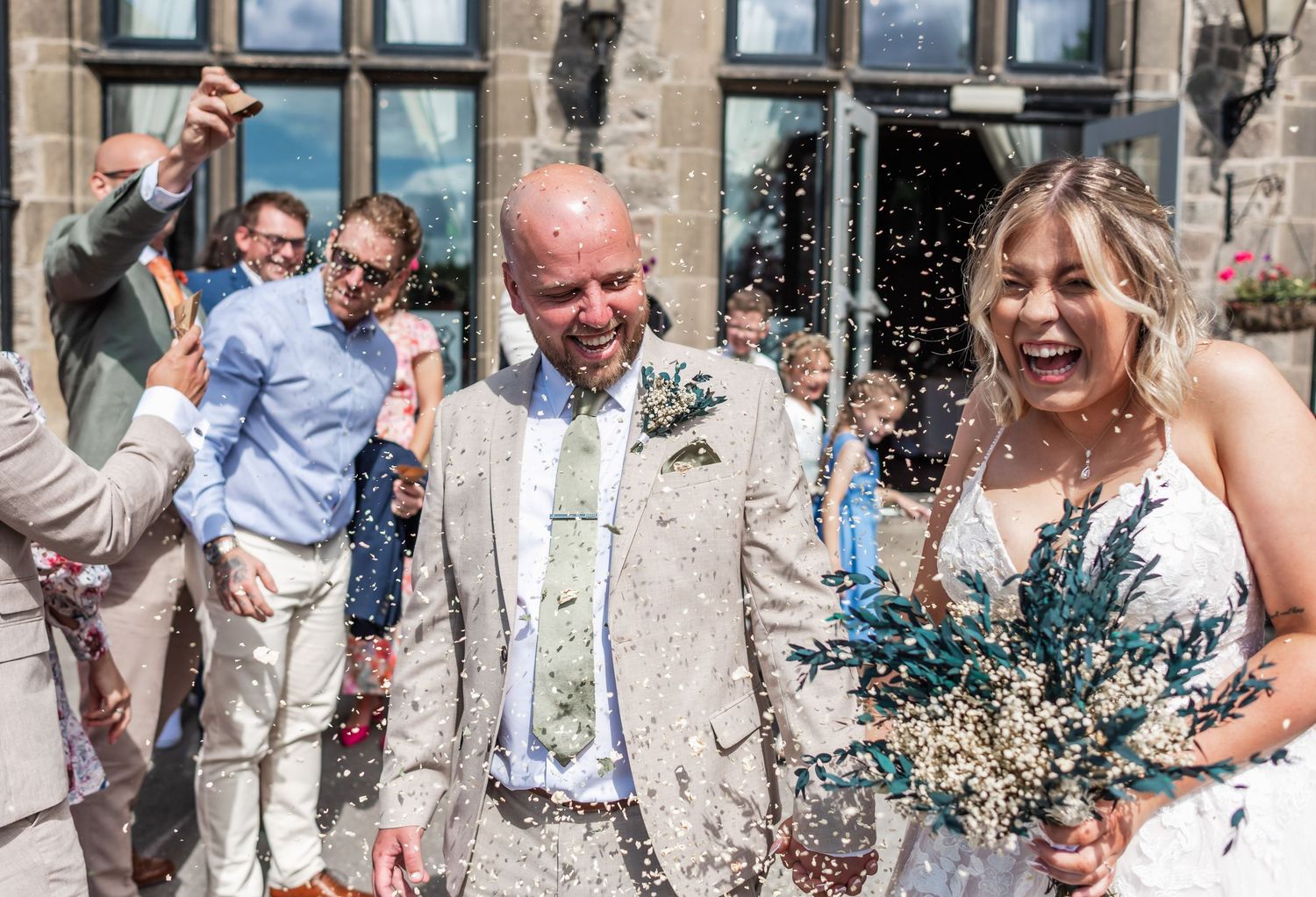 Celebration with confetti outside a stone building during a wedding.