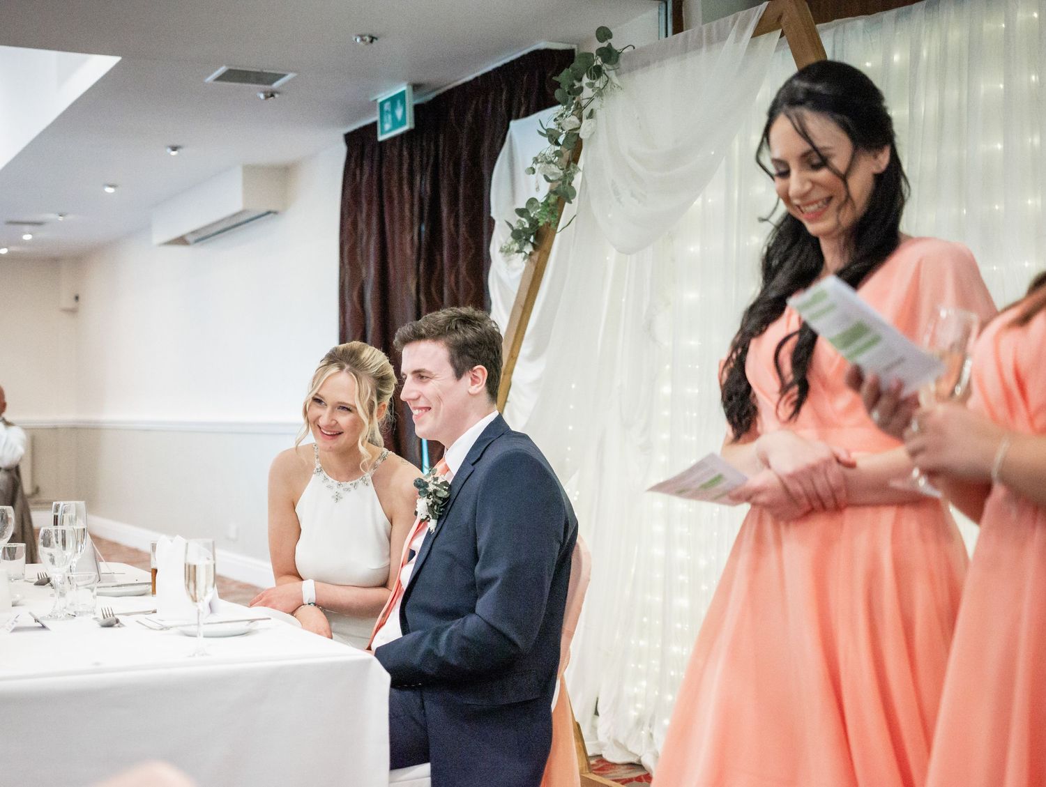 A reception celebration with coral-colored bridesmaid dresses and elegant white decor.