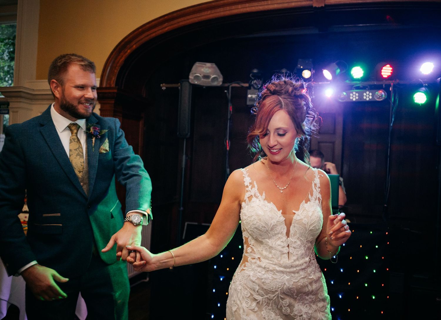 A couple dances under colorful stage lights during their wedding reception.