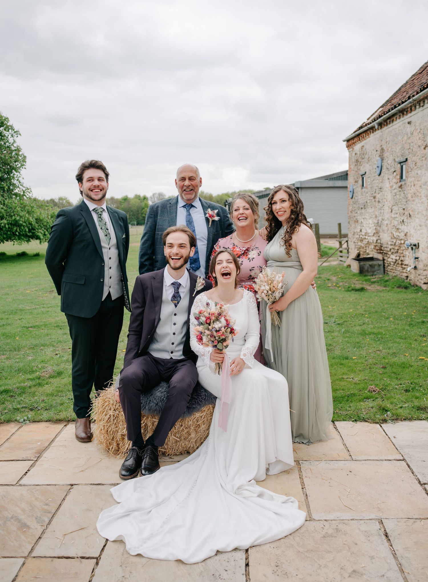Wedding party poses for group photos on rustic stone patio.