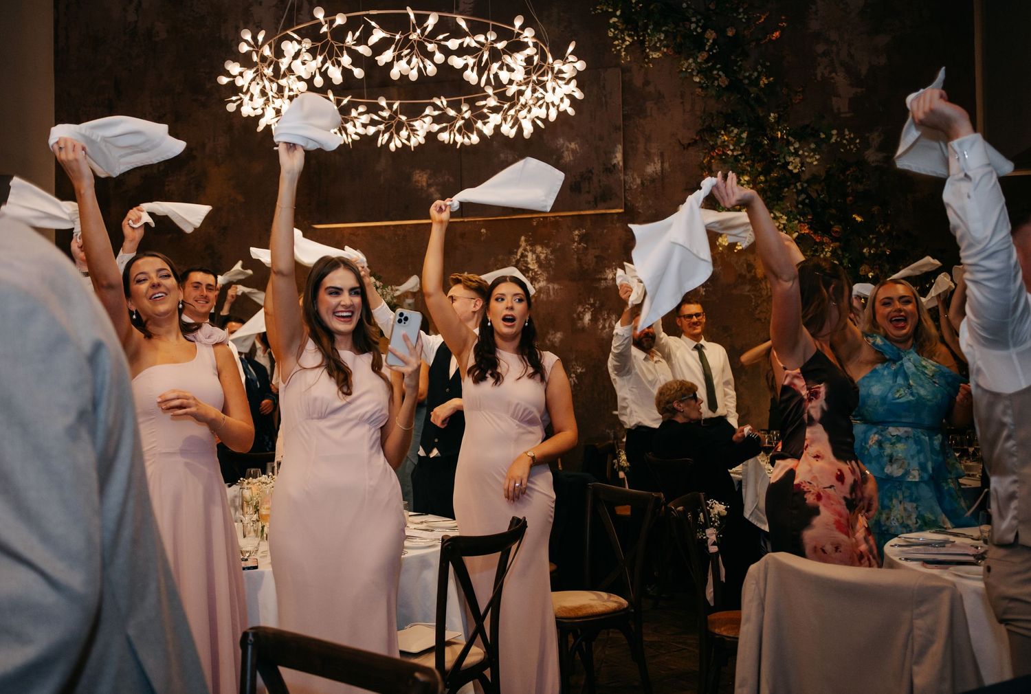 Wedding reception celebration with guests dancing under illuminated leaf pattern lighting effects.