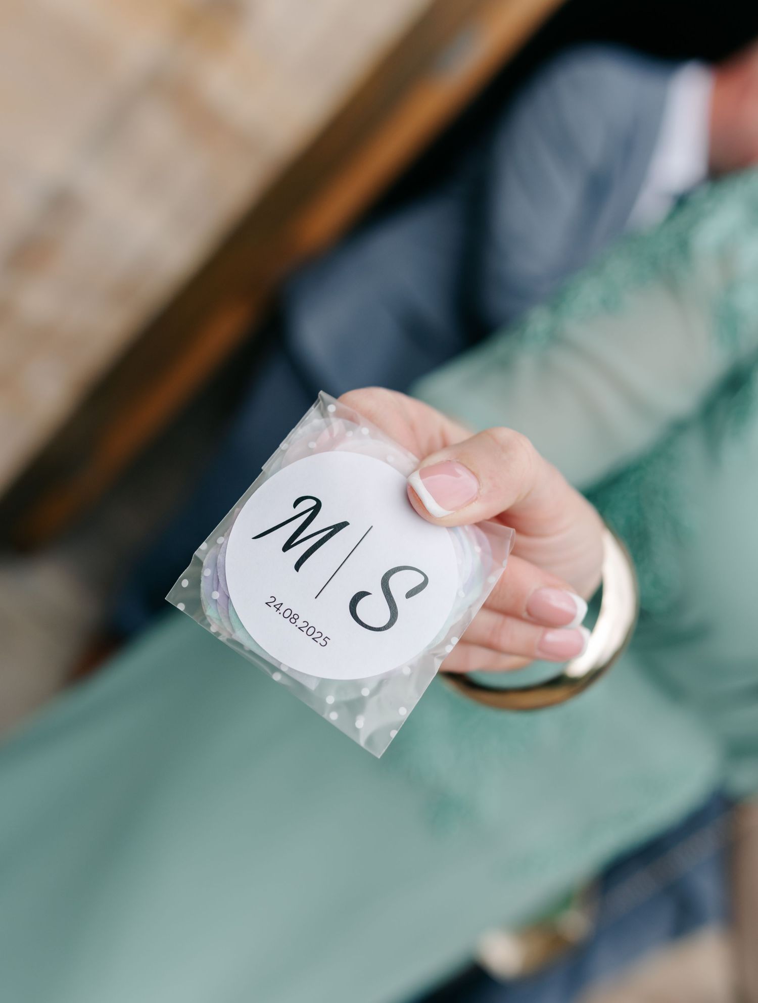 Close-up shot of hands holding wedding detail cards with initials.