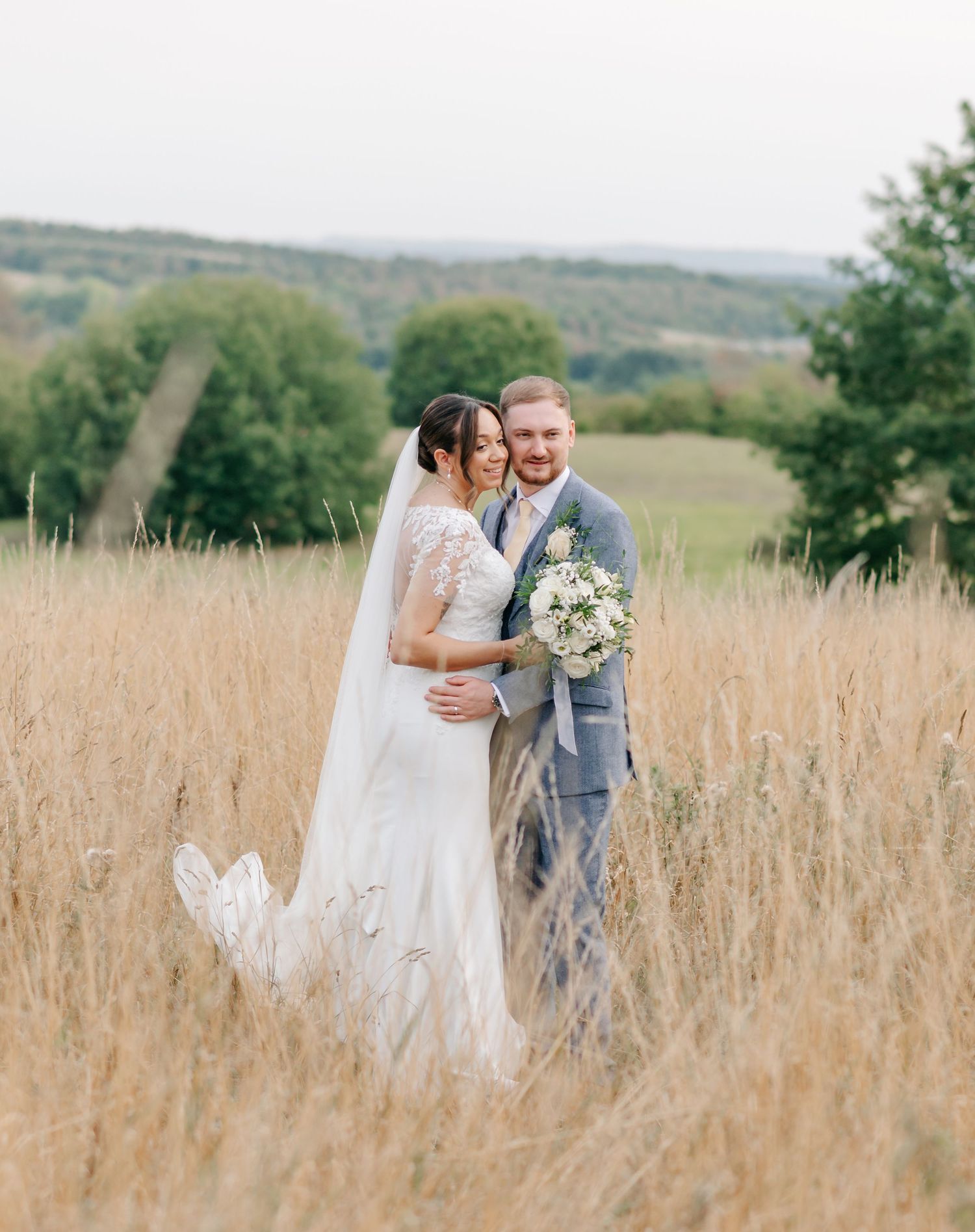 A newlywed couple embraces in a golden wheat field during their romantic wedding photoshoot.