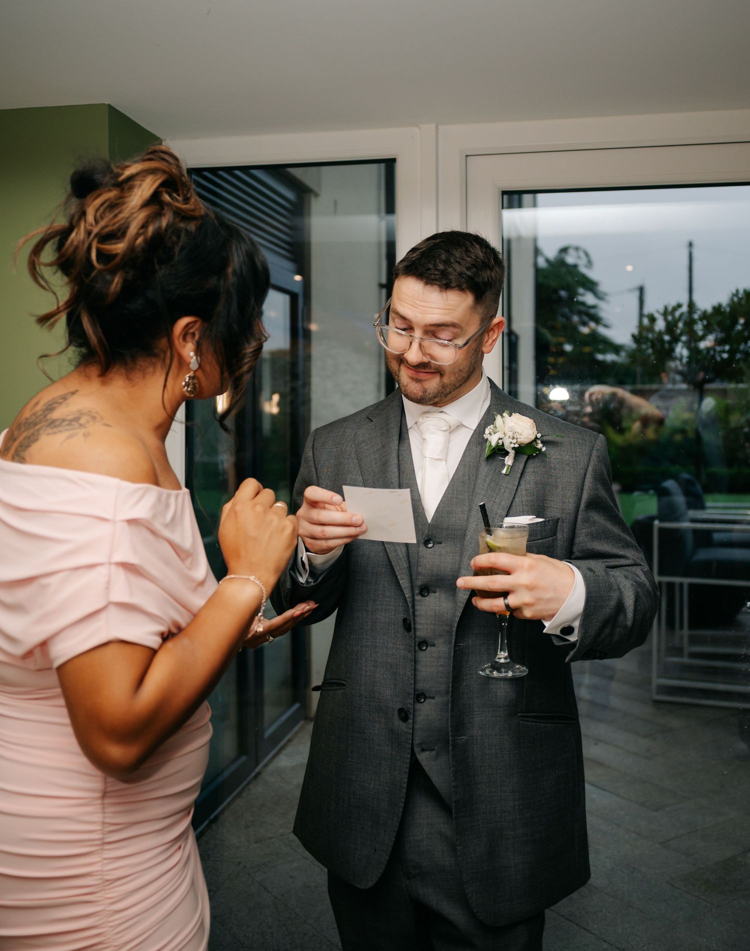 A couple shares a moment during a wedding celebration, with the groom holding a drink.