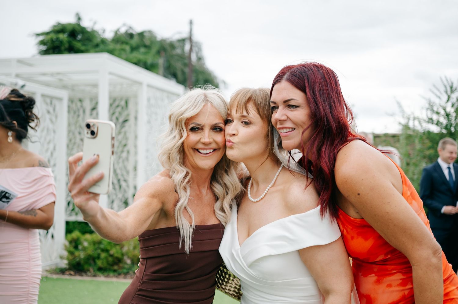 Wedding party members in colorful dresses pose together for fun photos outdoors.